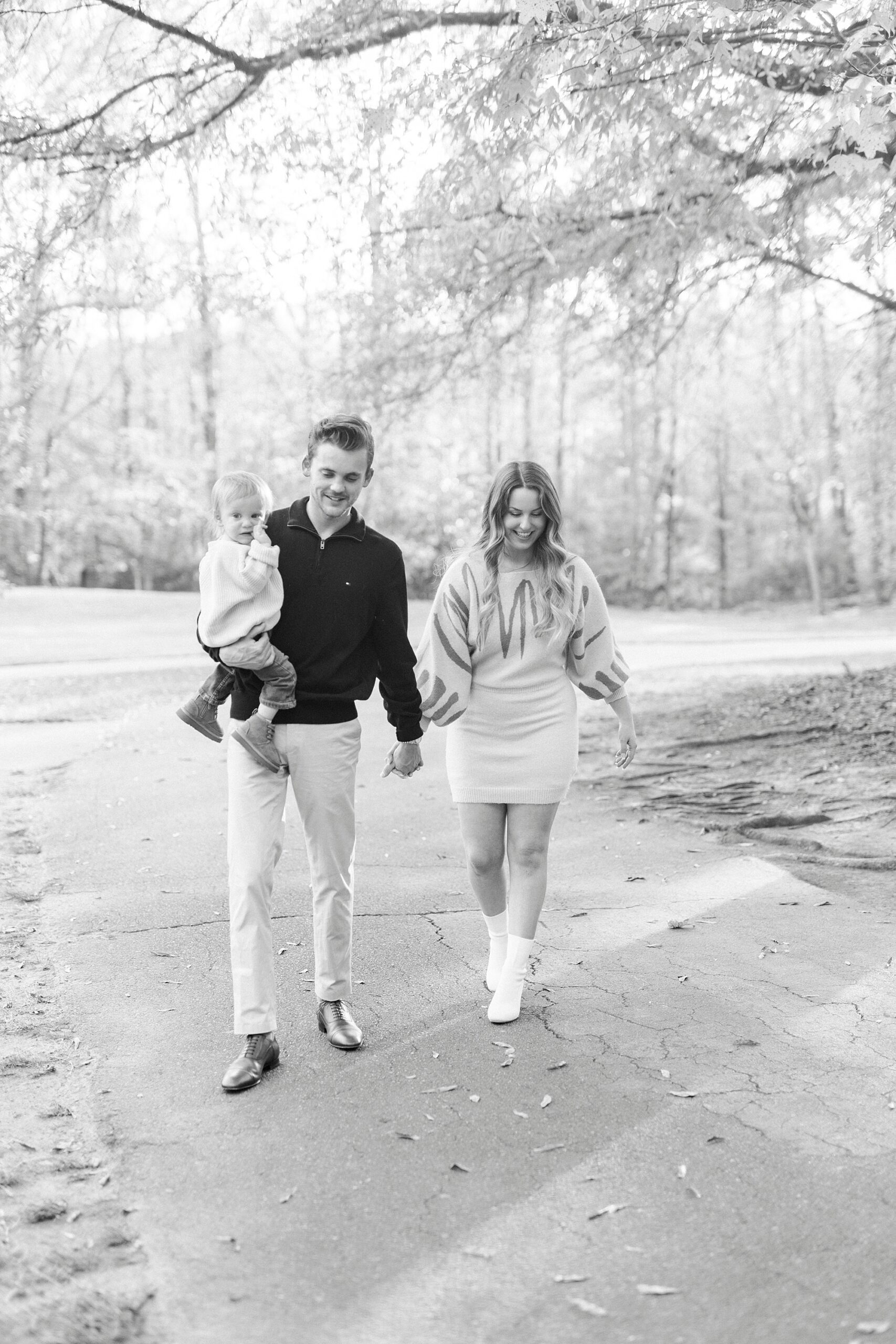 parents walk through Baker's Creek Park holding hands and dad carries son