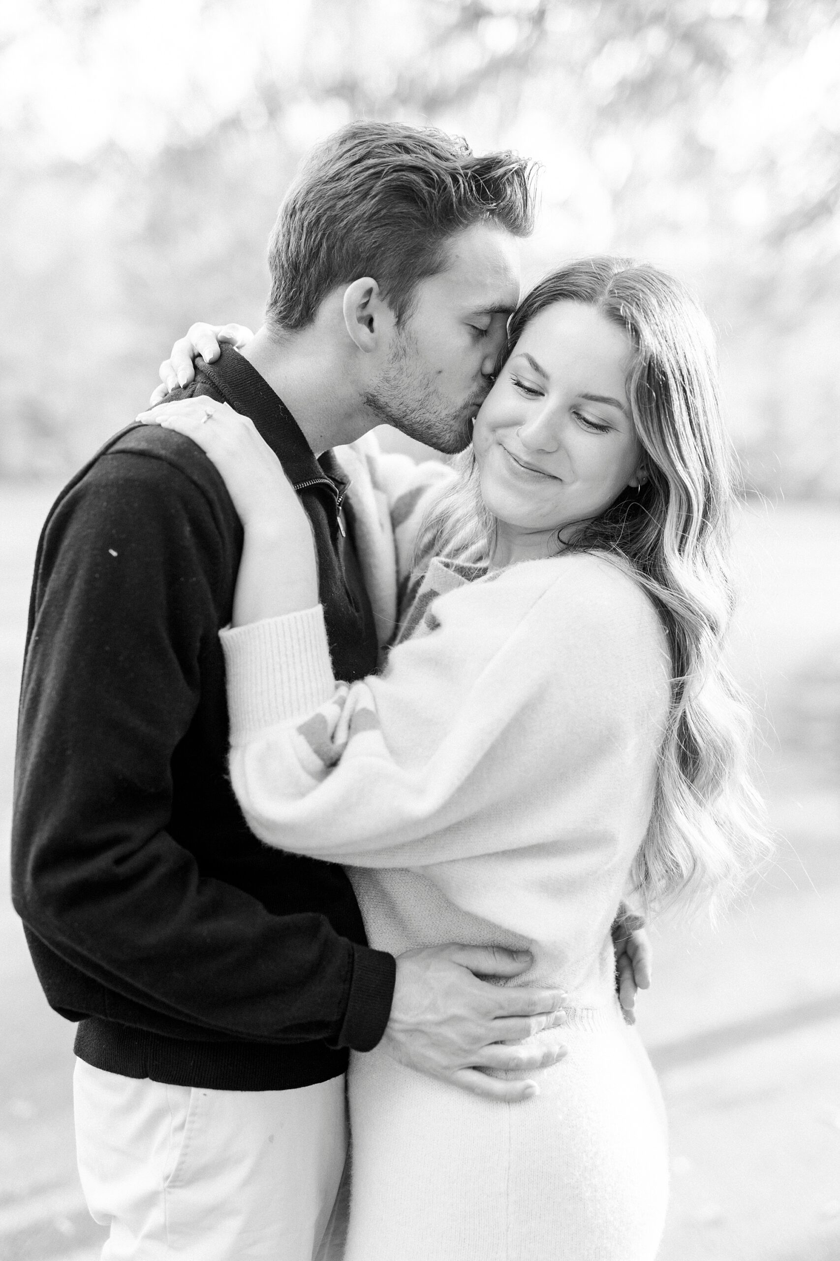 man kisses woman's cheek while she scrunches her eyes closed 