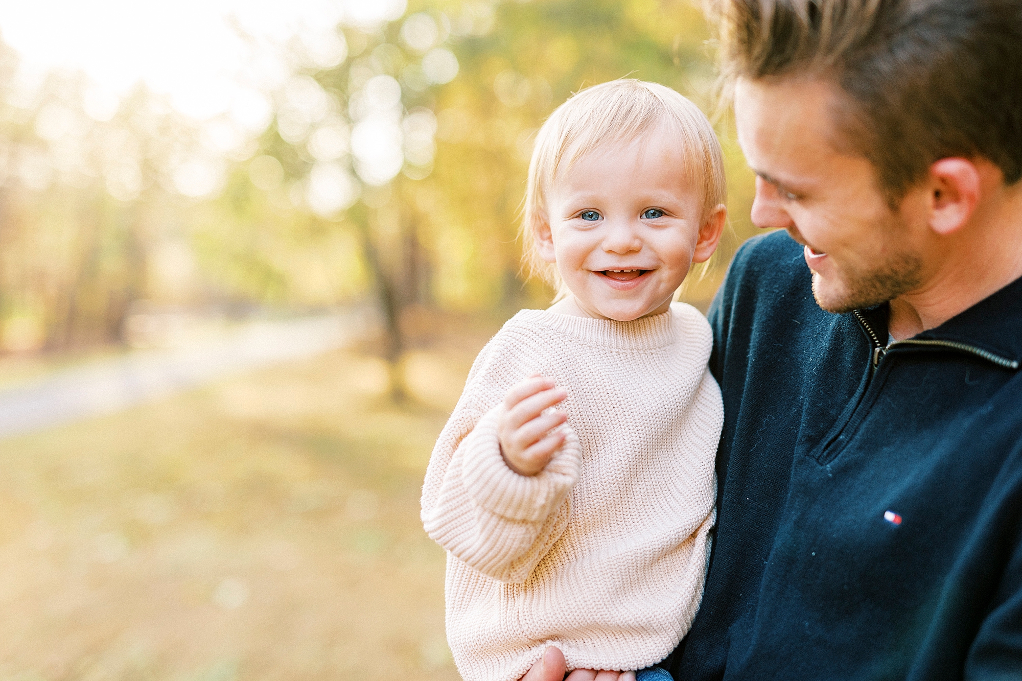 toddler smiles during fall family photos in Baker's Creek Park
