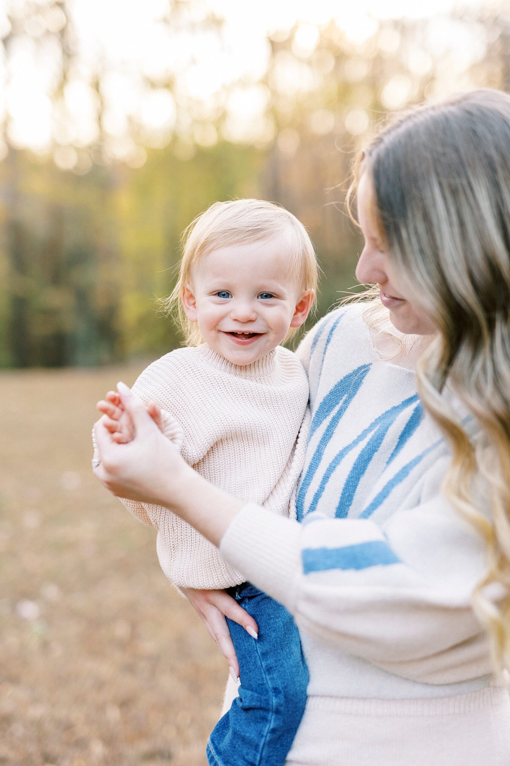 mom holds son's hand while holding him on her hip inside Baker's Creek Park