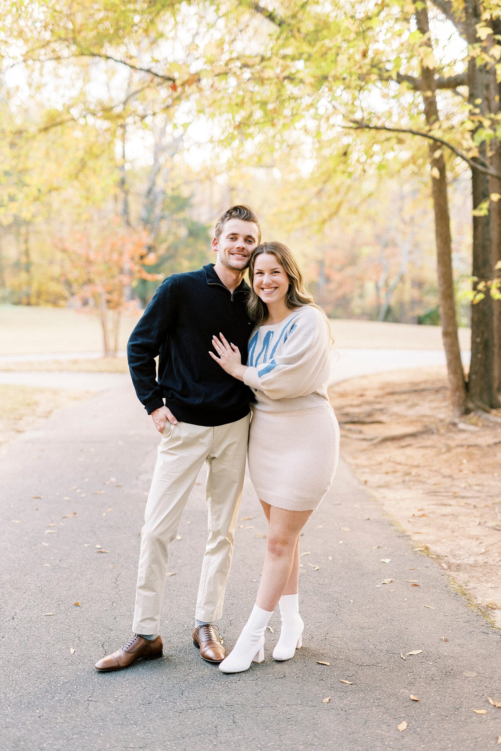 woman stands with legs crossed leaning into fiancee inside Baker's Creek Park