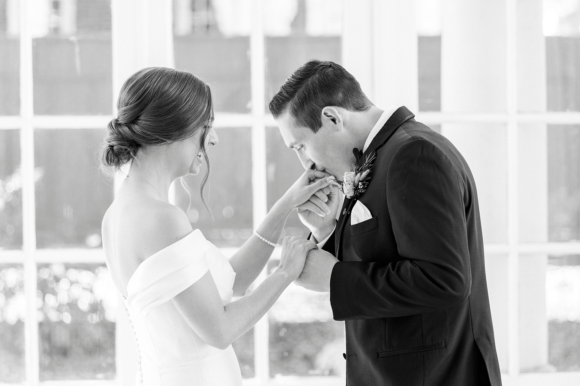 groom leans to kiss bride's hand during first look inside Separk Mansion
