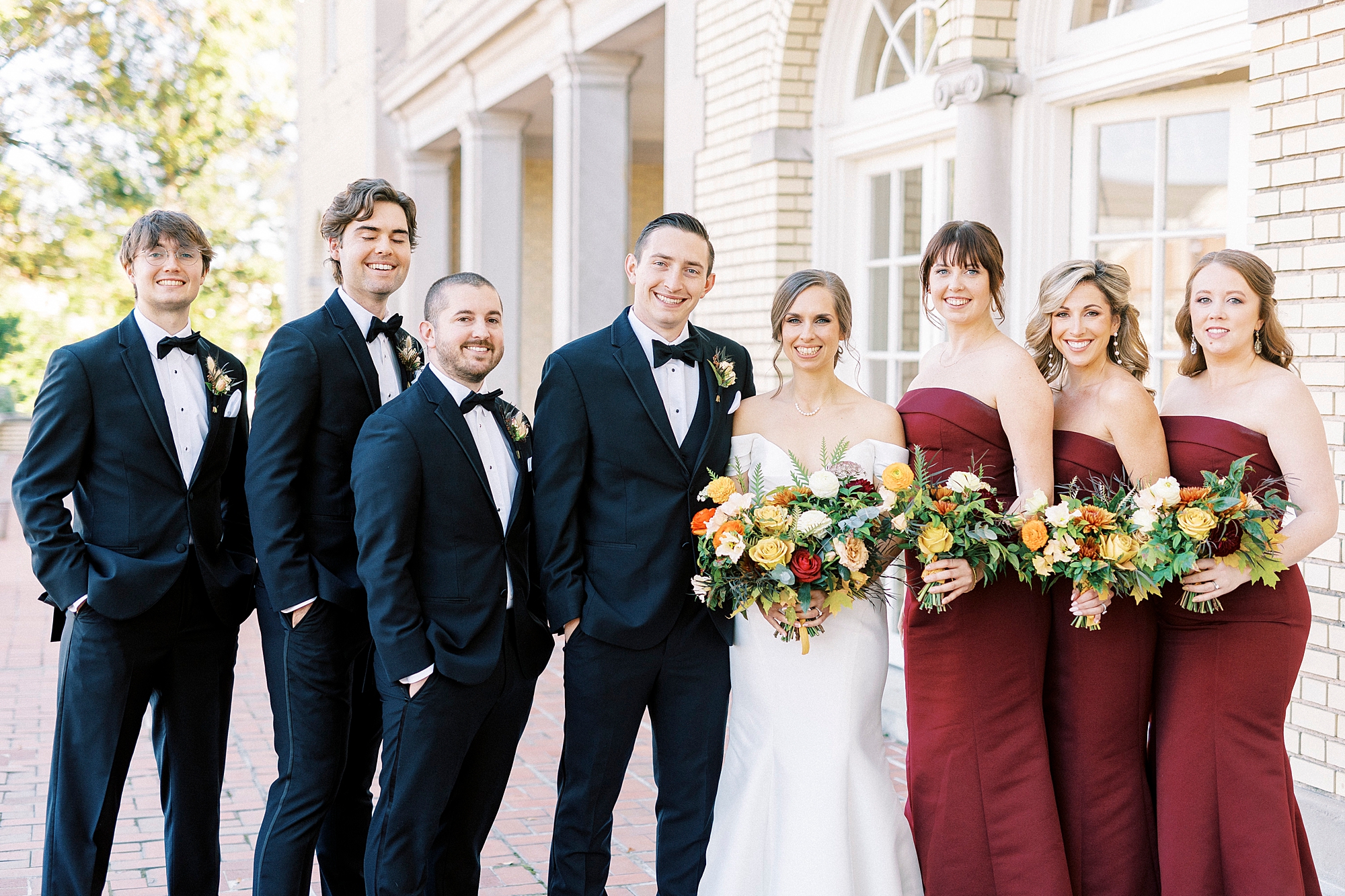 bride and groom pose with wedding party outside Separk Mansion with red and black attire