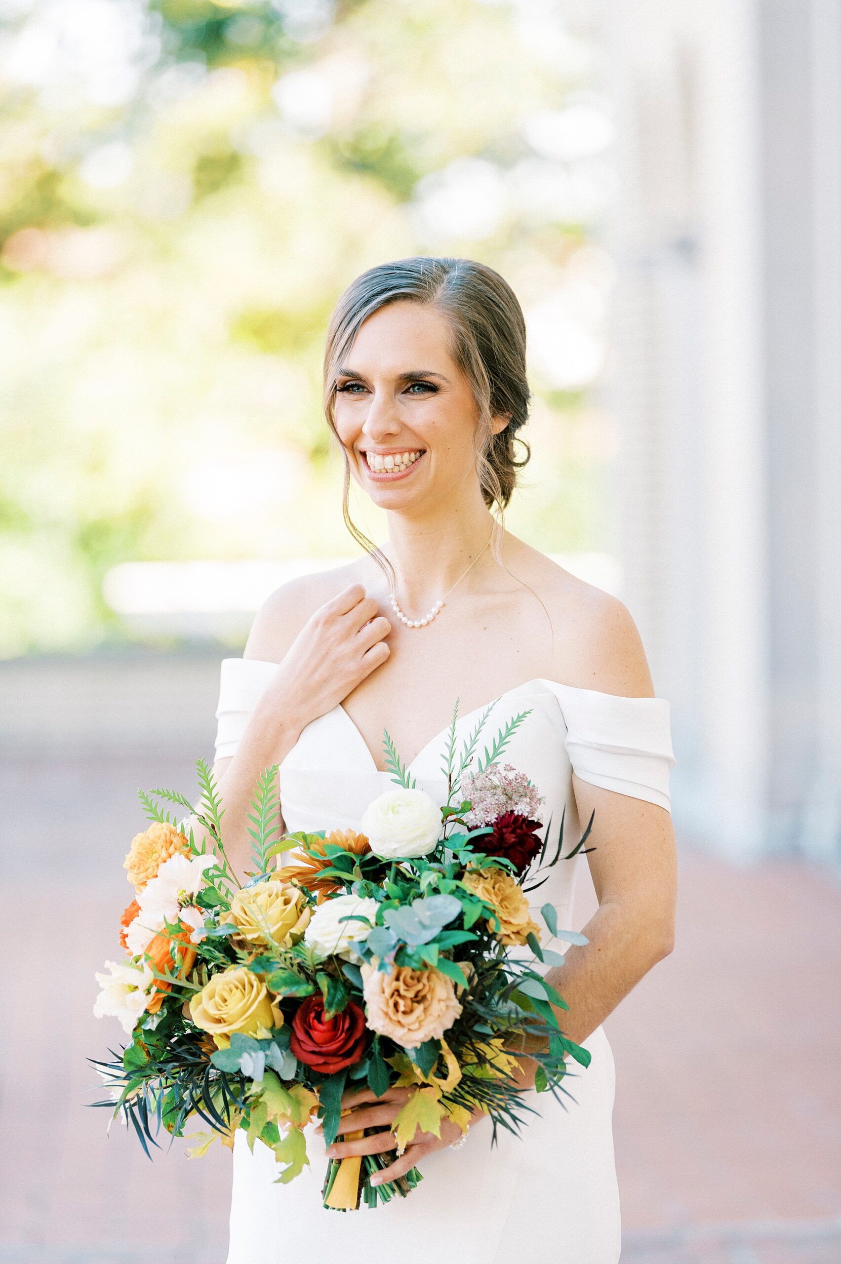 bride stands on patio with hand above neckline of wedding dress at Separk Mansion
