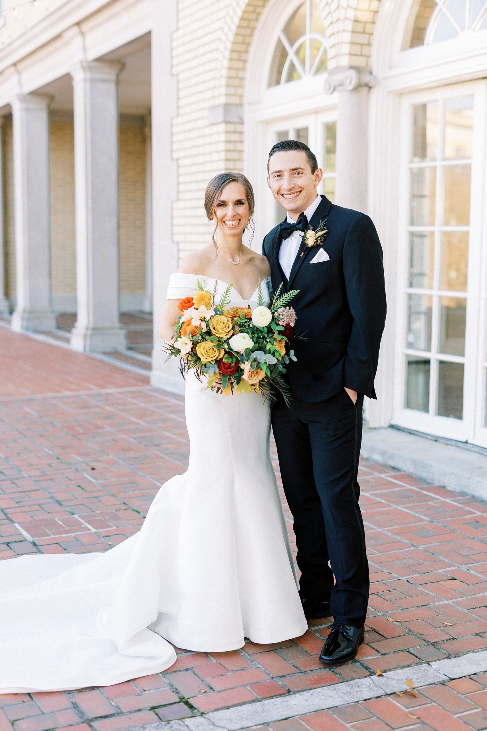 bride and groom hug on patio outside Separk Mansion on fall wedding day