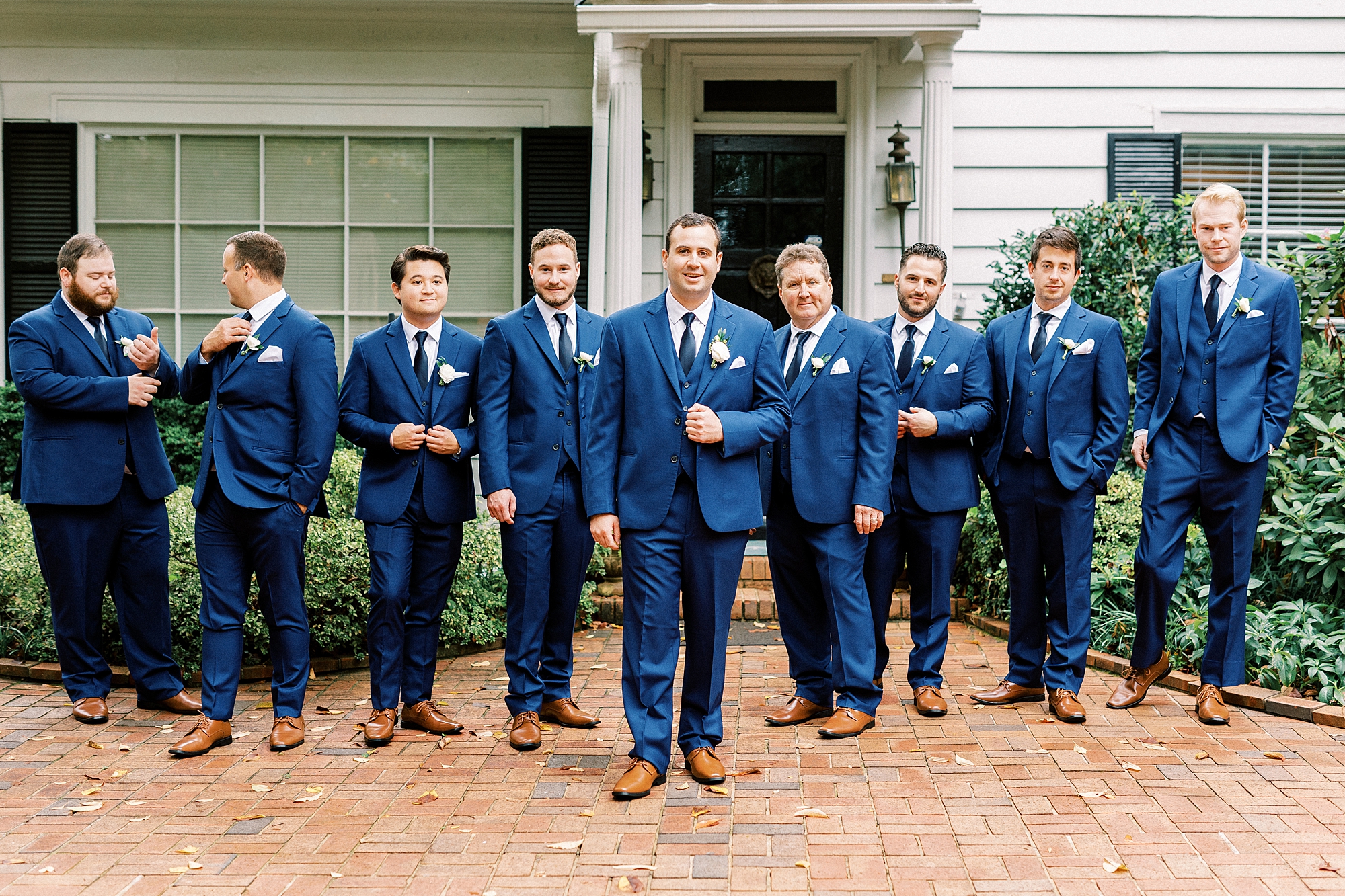 groom and groomsmen walk in navy suits outside the Morehead Inn