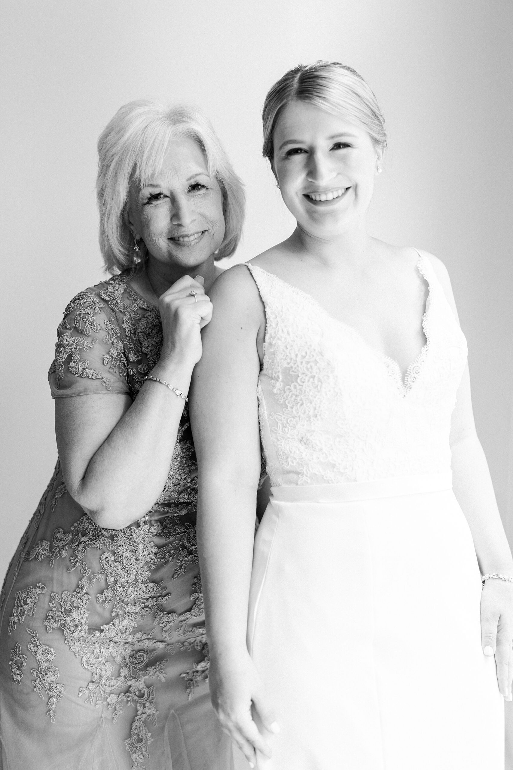 bride smiles with mother hugging her during suite at the Morehead Inn