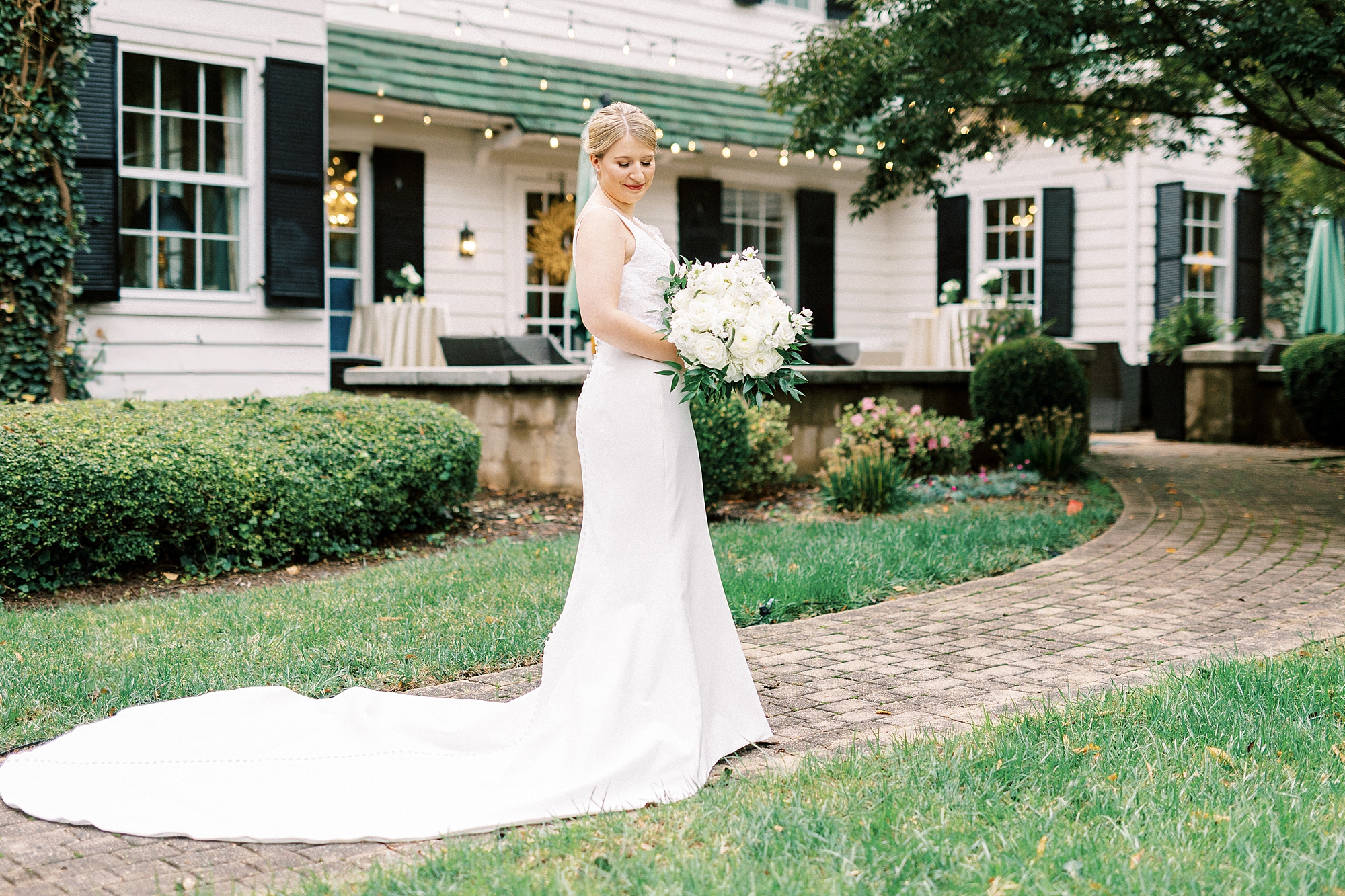 bride looks down over shoulder with veil around her holding bouquet of ivory flowers