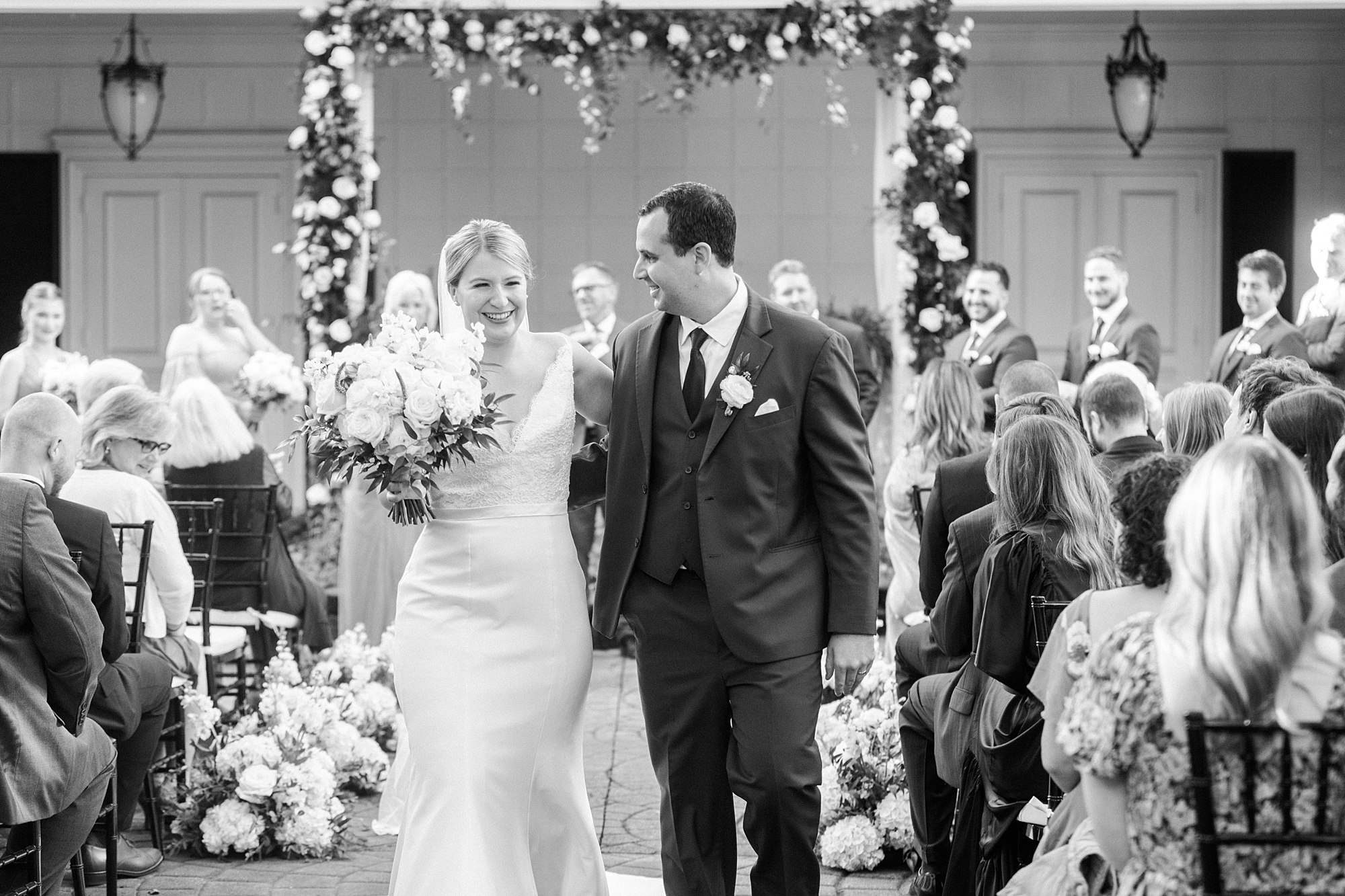 newlyweds hold hands walking up aisle after ceremony at the Morehead Inn