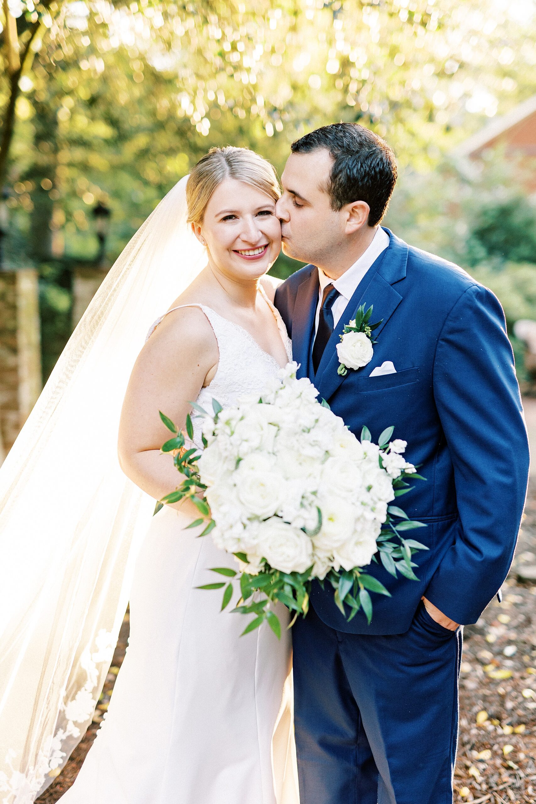 groom kisses bride's cheek during sunset wedding portraits at the Morehead Inn