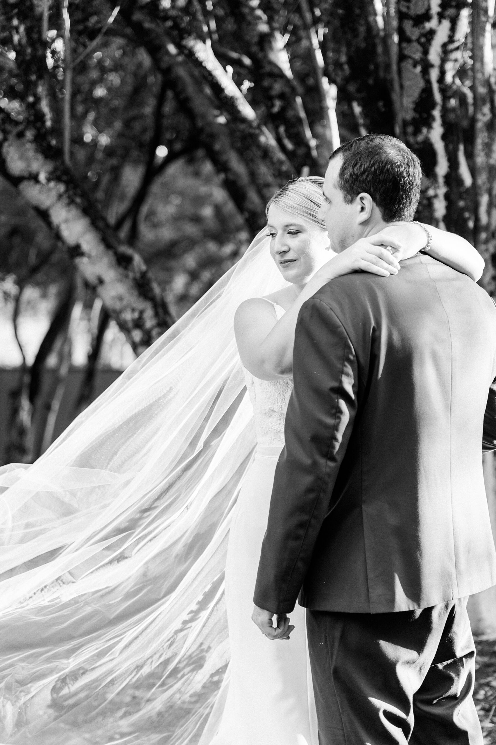 bride and groom hug at sunset at the Morehead Inn with bride's veil floating behind them