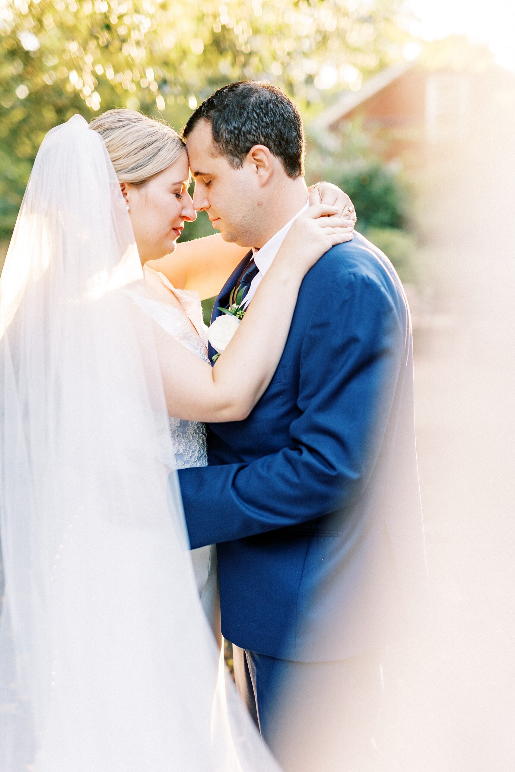 bride and groom hug with veil pulled up by camera