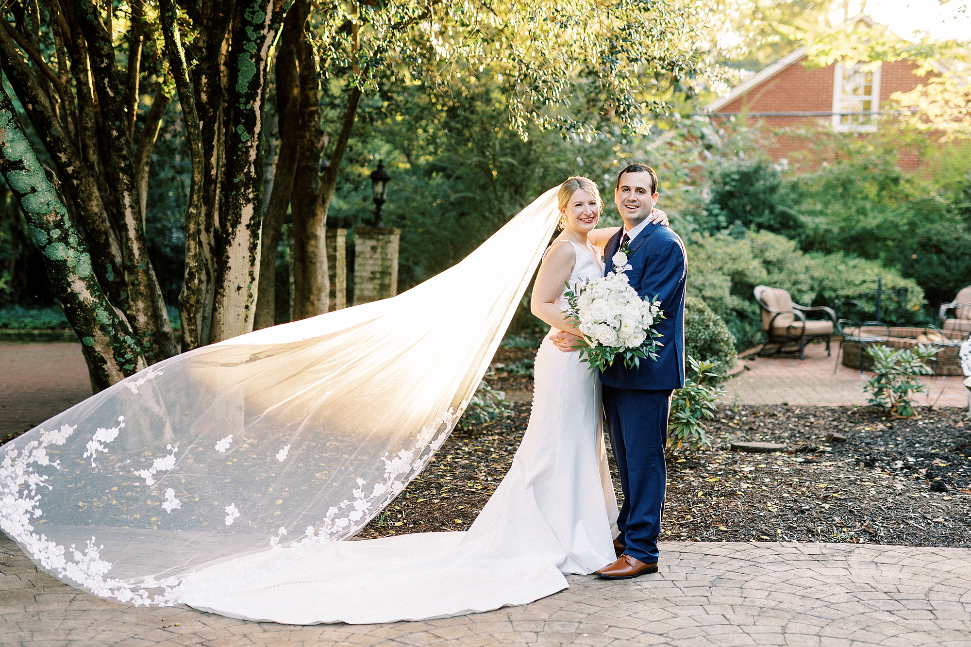 groom hugs bride around waist with veil floating behind them