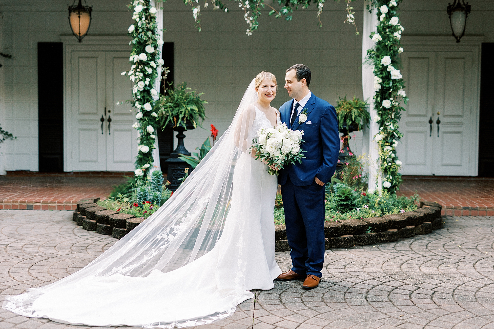 groom in blue suit looks at bride hugging her beside him