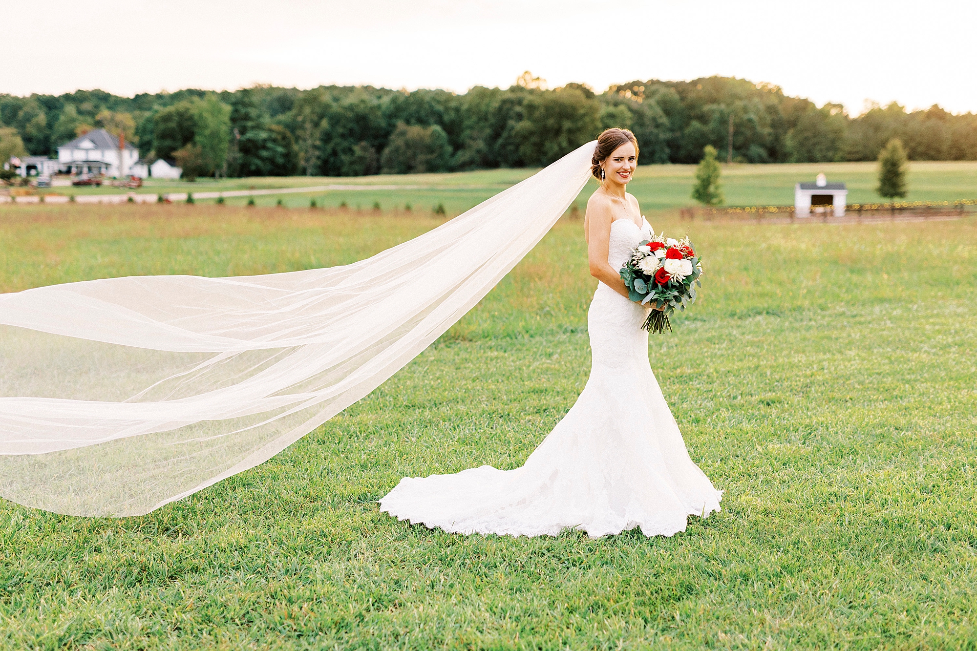 bride smiles holding bouquet of white and red flowers 
