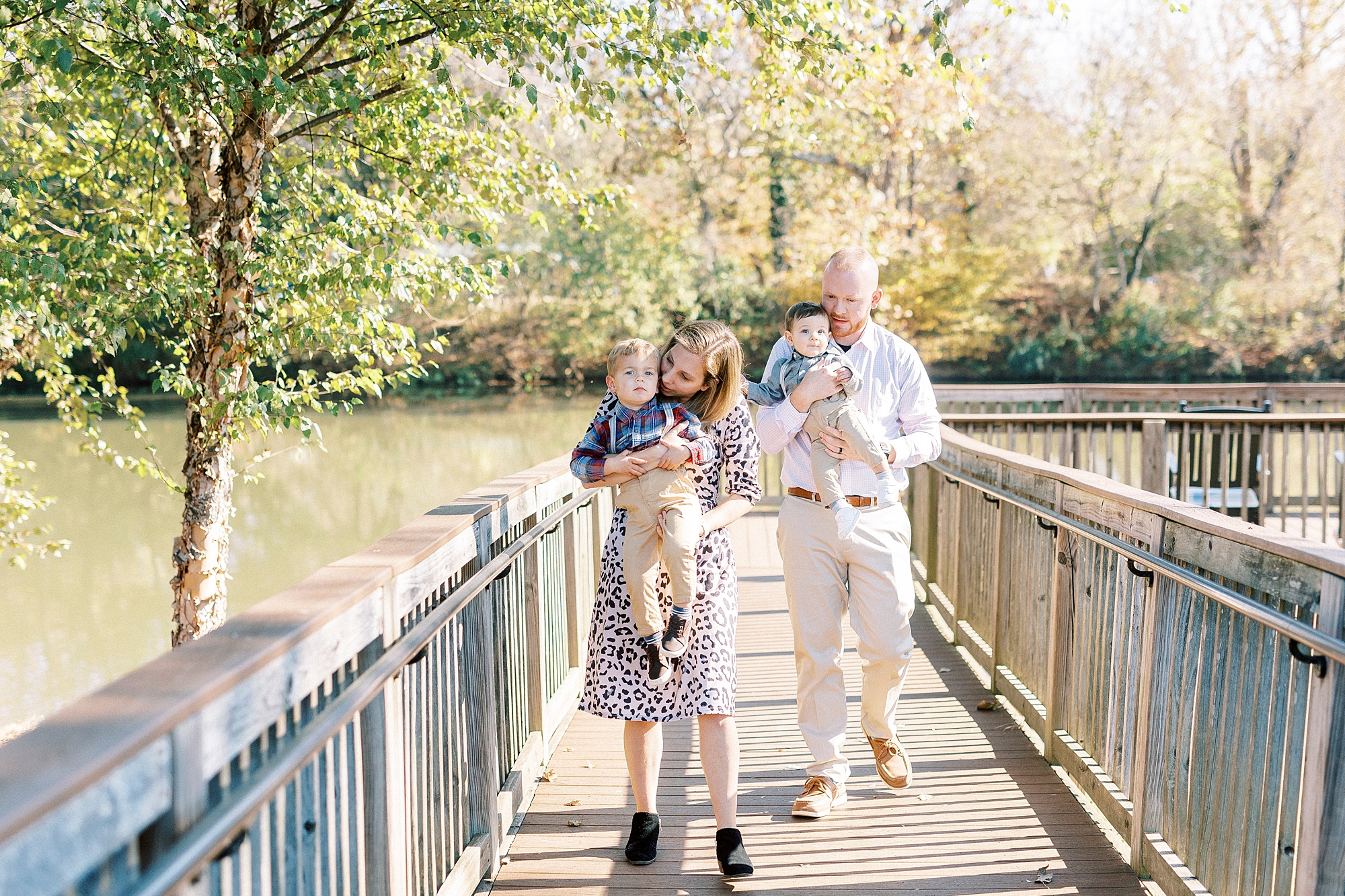 parents carry two sons across bridge during lifestyle fall family portraits in North Carolina 