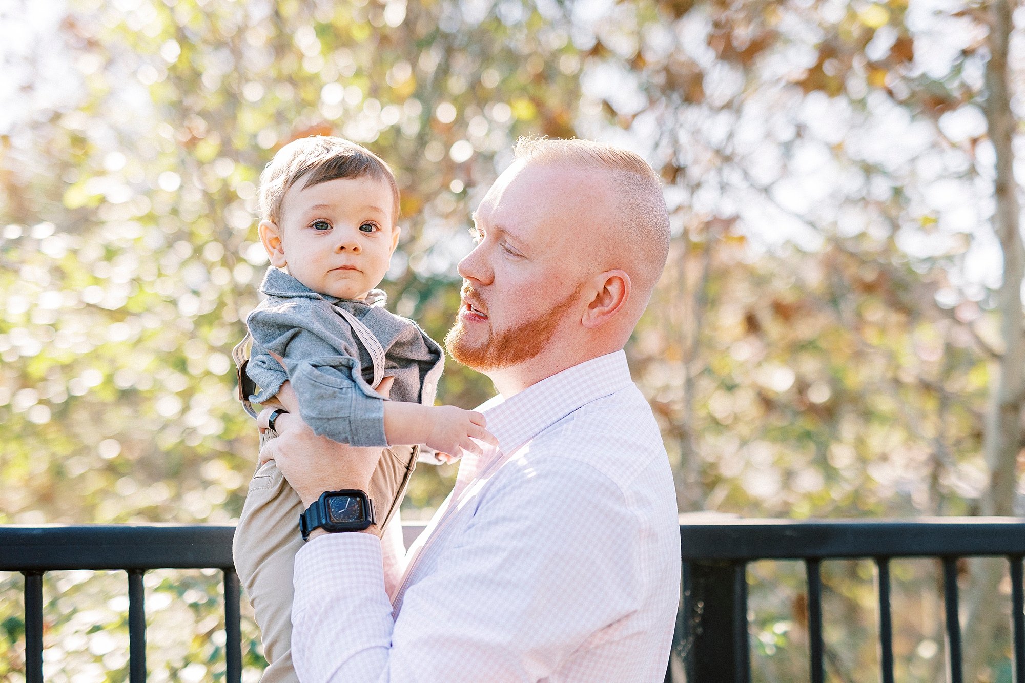 dad lifts up son standing on bridge during lifestyle fall family portraits