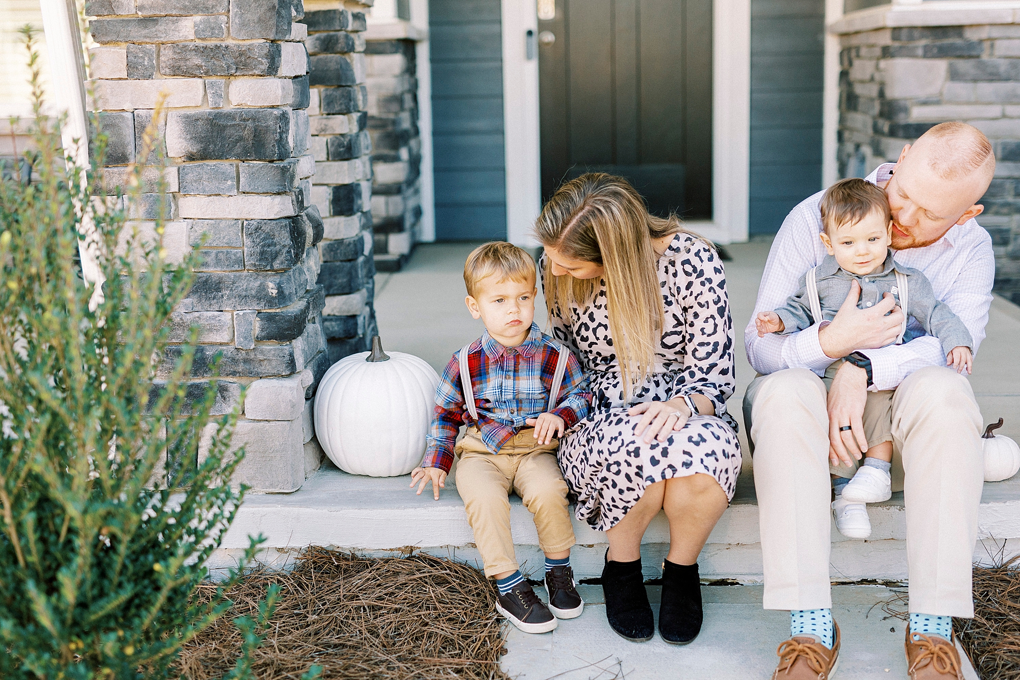 mom hugs son and looks down at him sitting on front porch of Cramerton NC home 