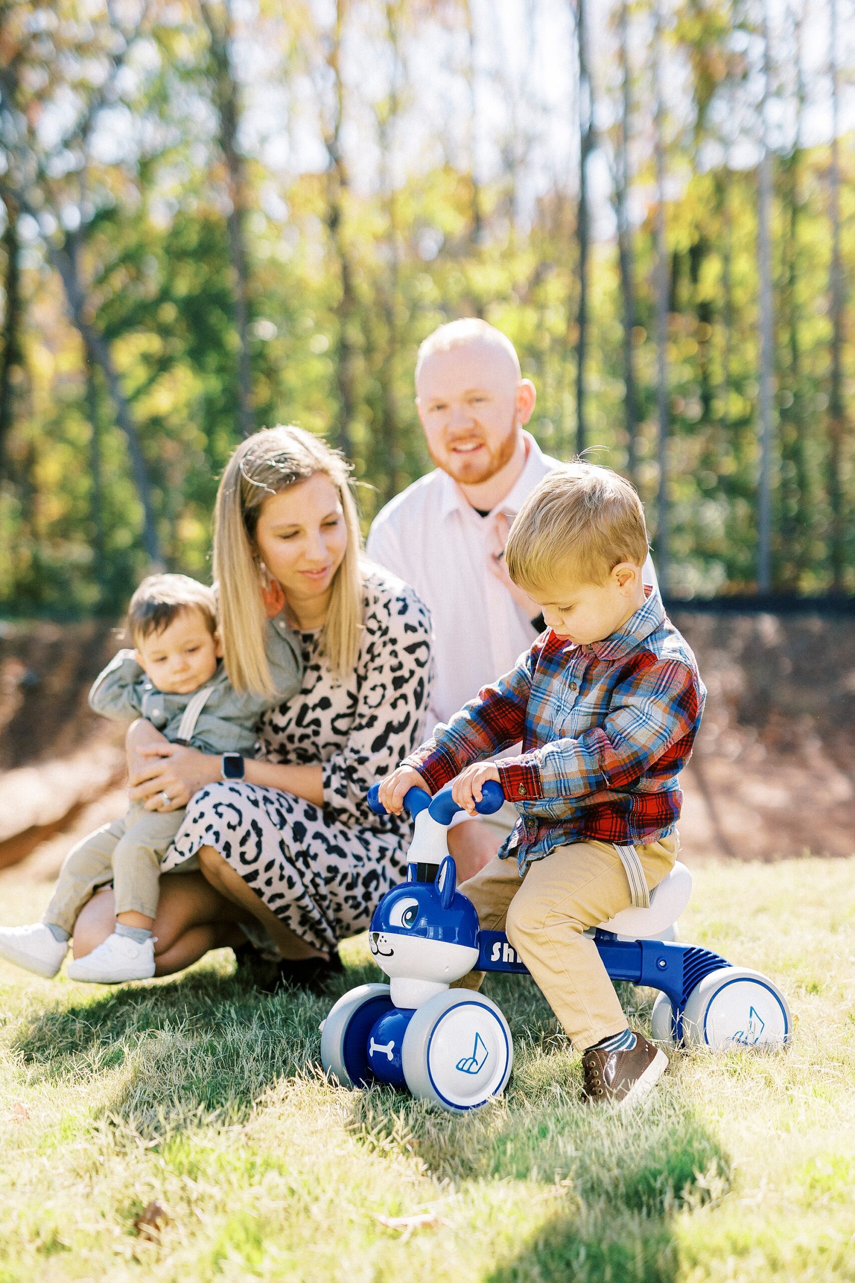 toddler rides bike in grass outside home by parents in NC