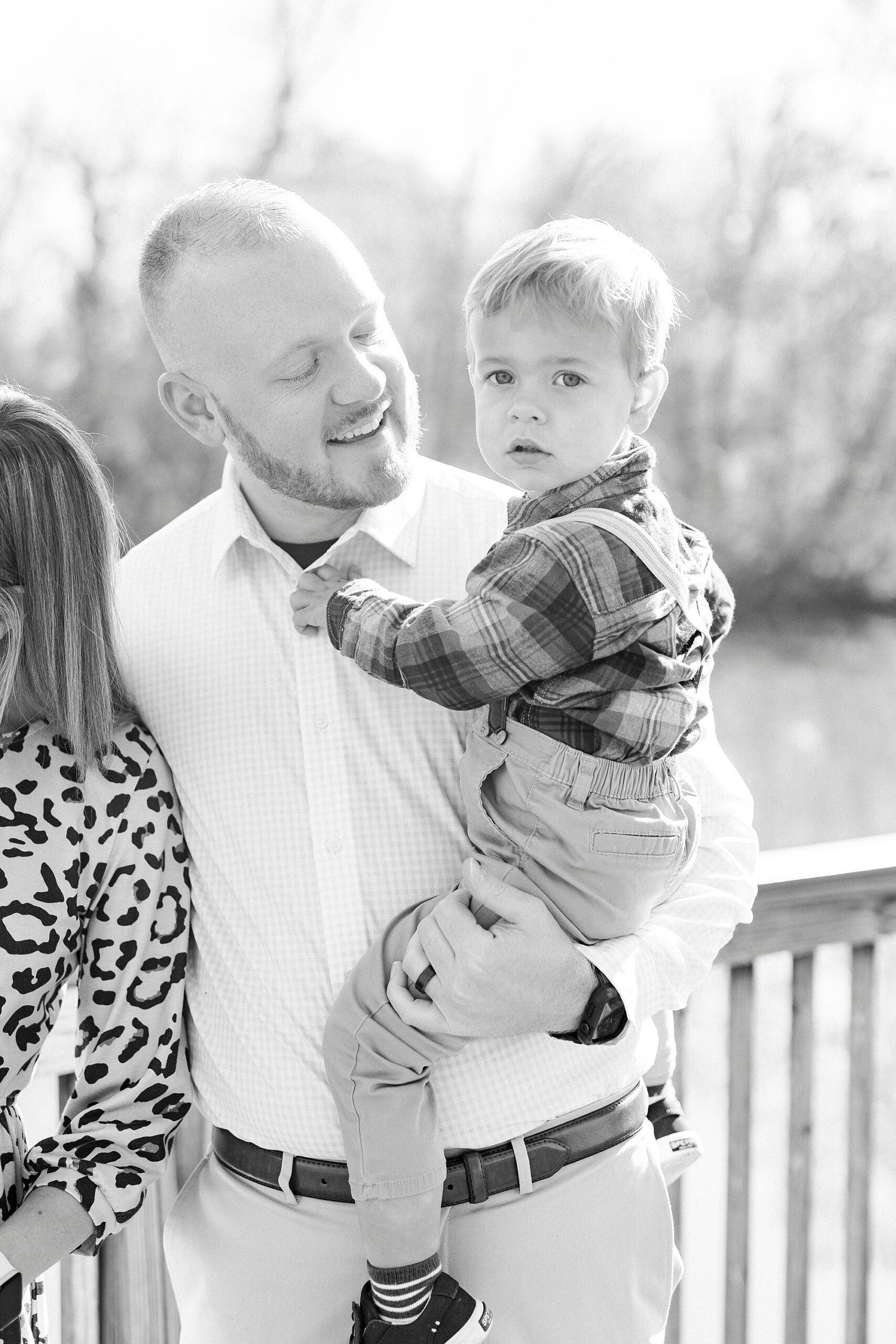 dad holds son on hip standing on wooden bridge during fall family photos in Cramerton NC