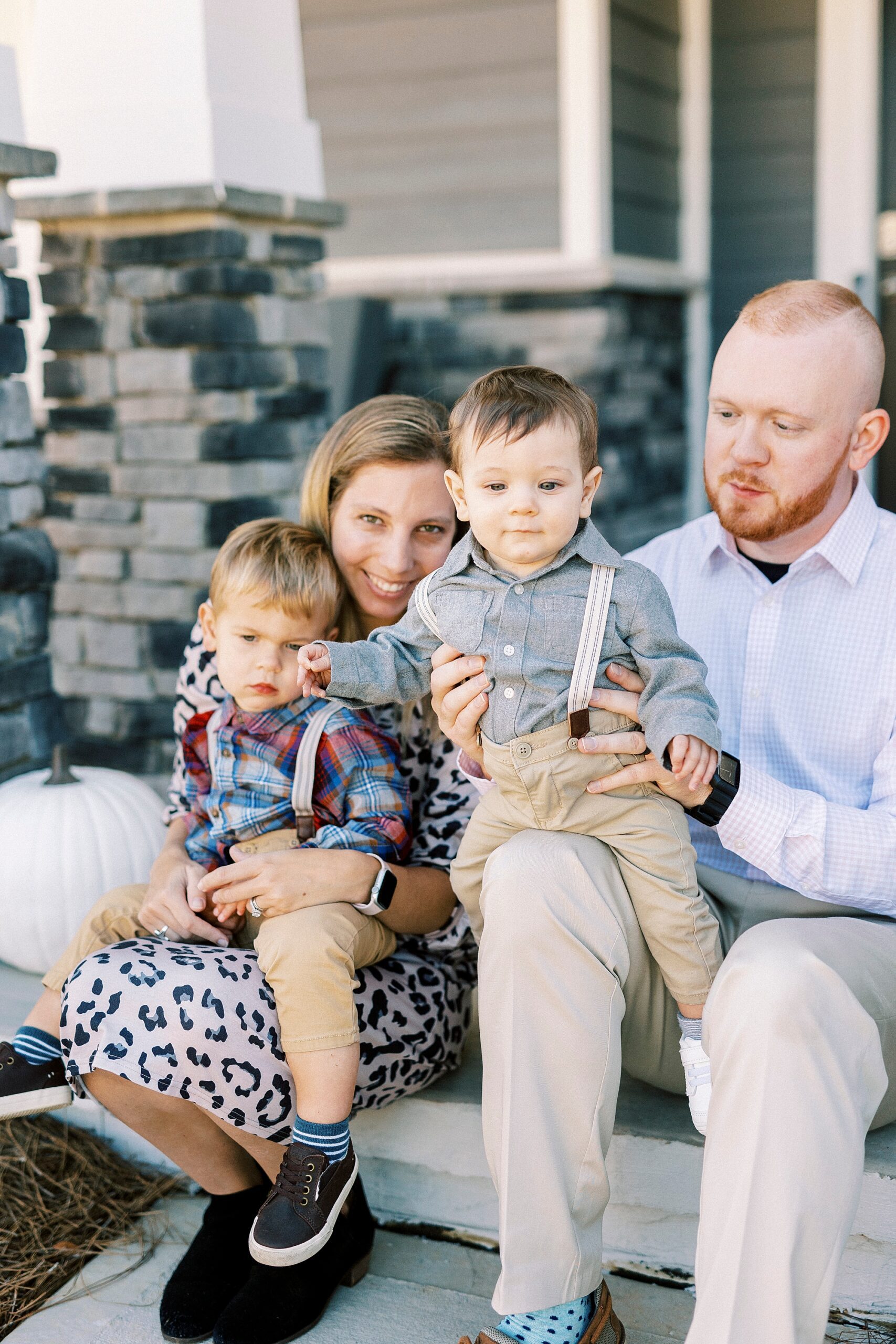 parents snuggle with two boys on stop of tips outside home