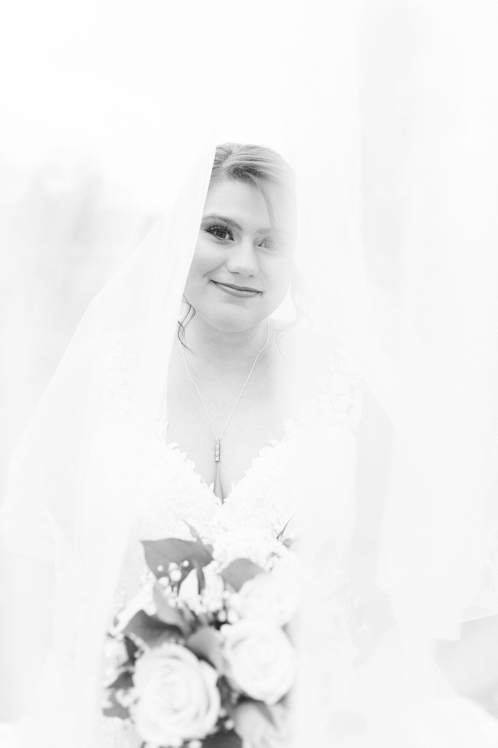 bride smiles holding bouquet of white and green flowers at the Farm at Brusharbor