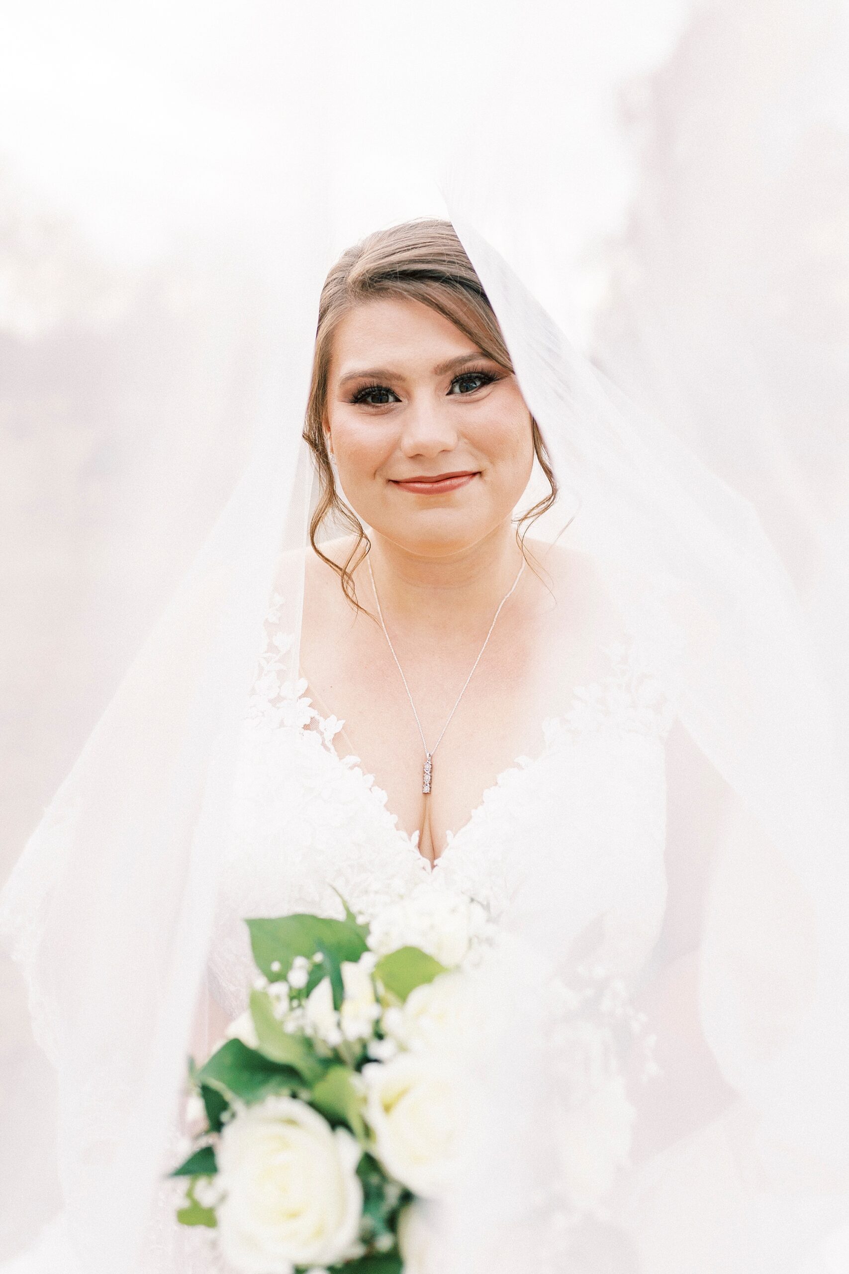 bride smiles with head tilted to left with veil over top of her