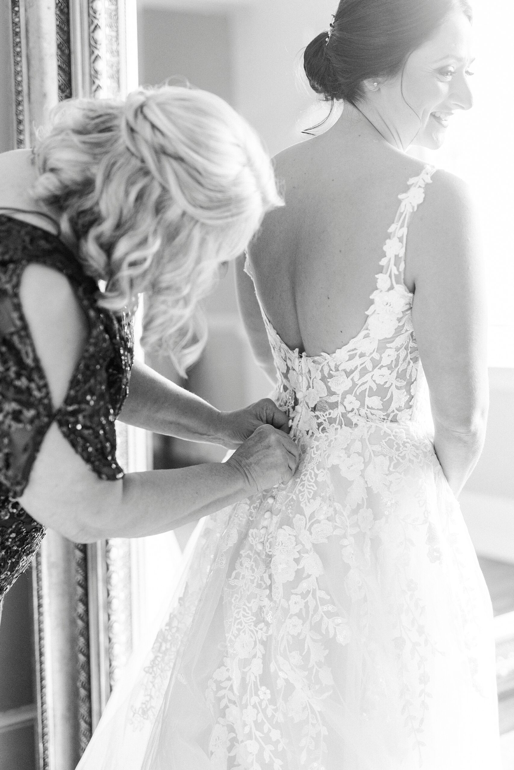 mother helps bride into wedding dress in suite at Separk Mansion