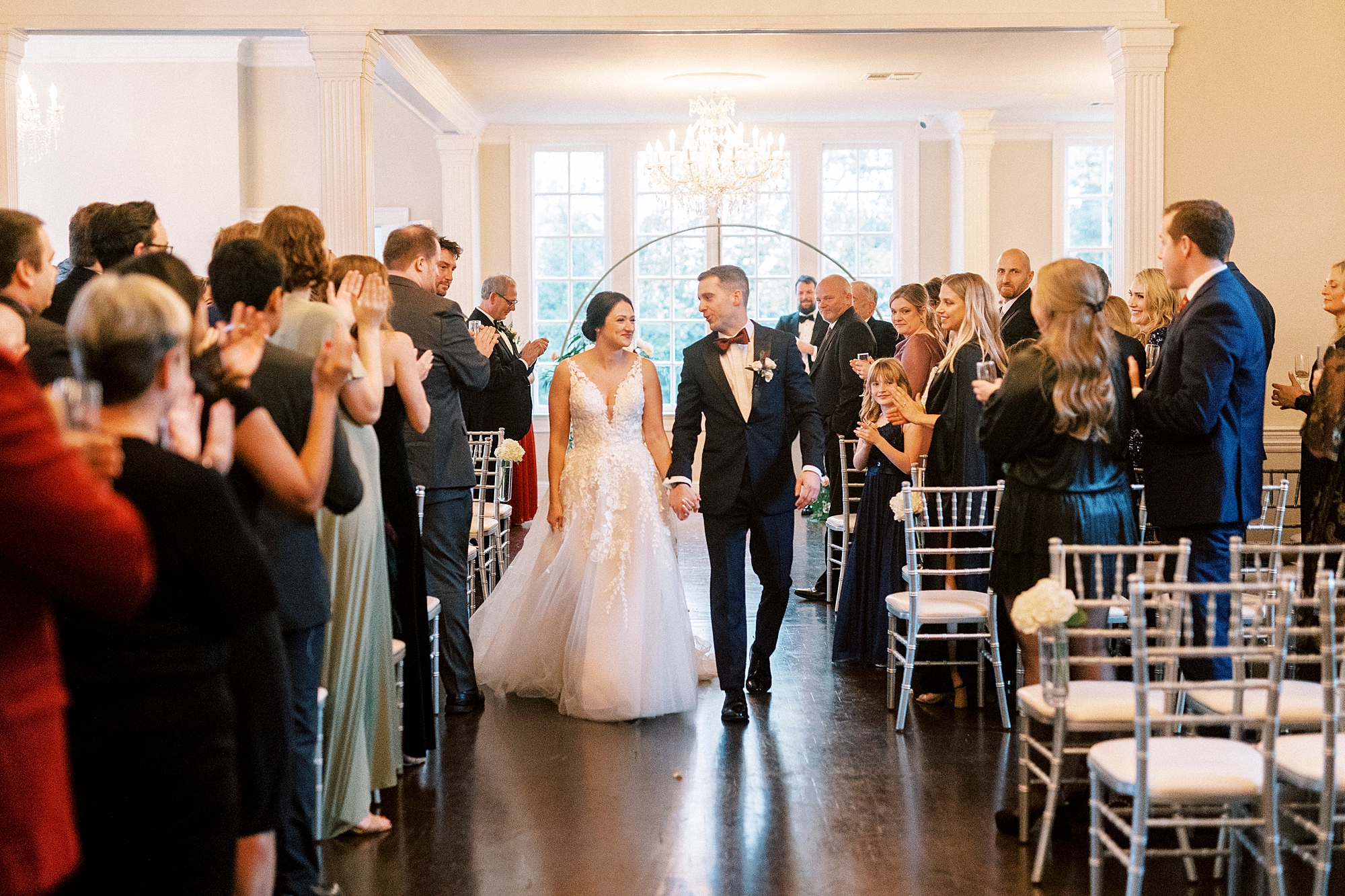 newlyweds hold hands leaving winter wedding ceremony at Separk Mansion