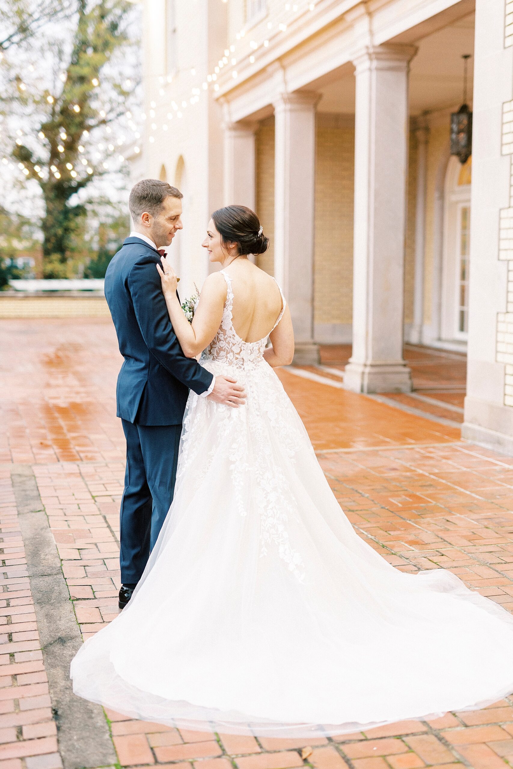 bride hugs groom showing off the back of her wedding gown 