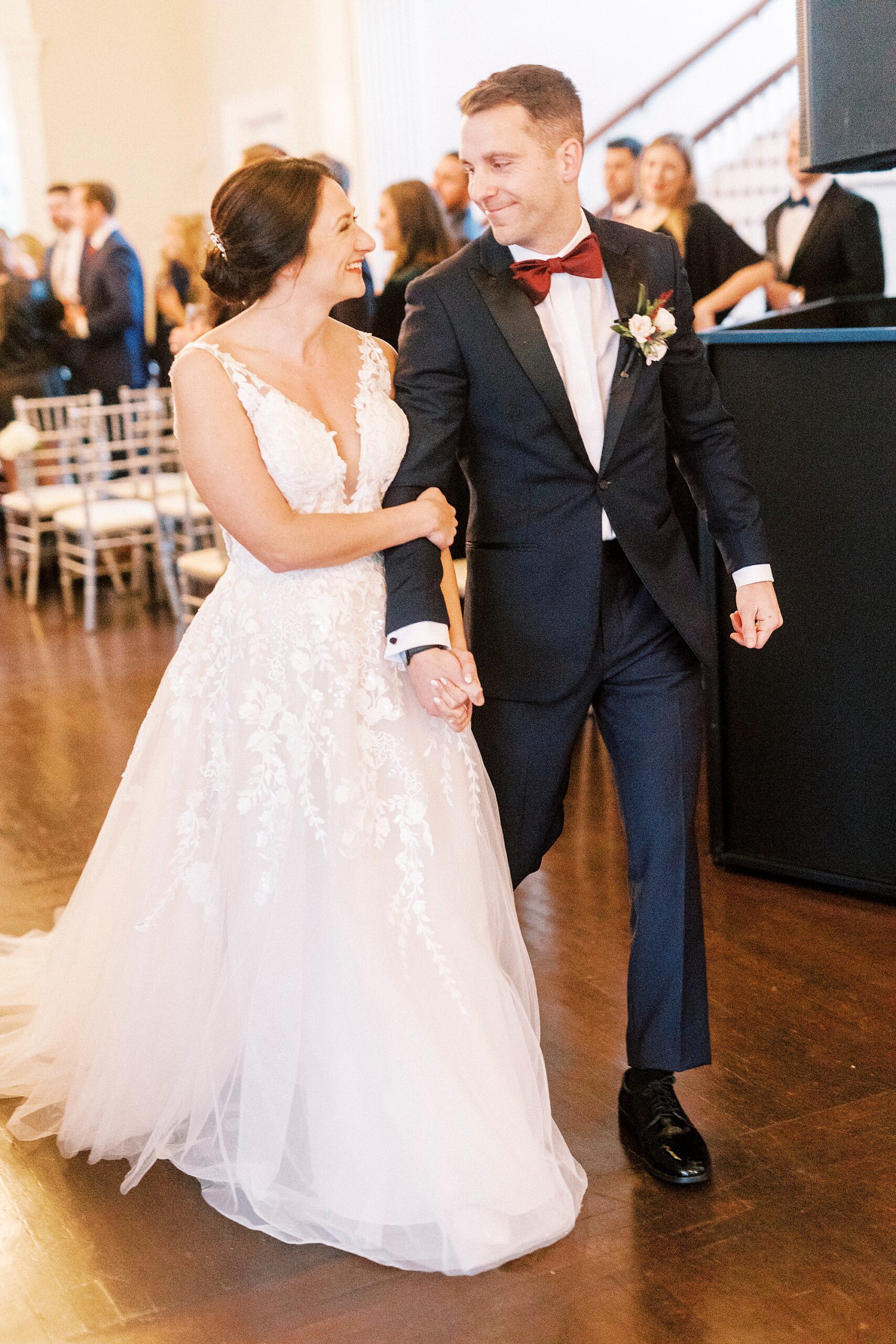 bride and groom hold hands leaving wedding ceremony inside mansion