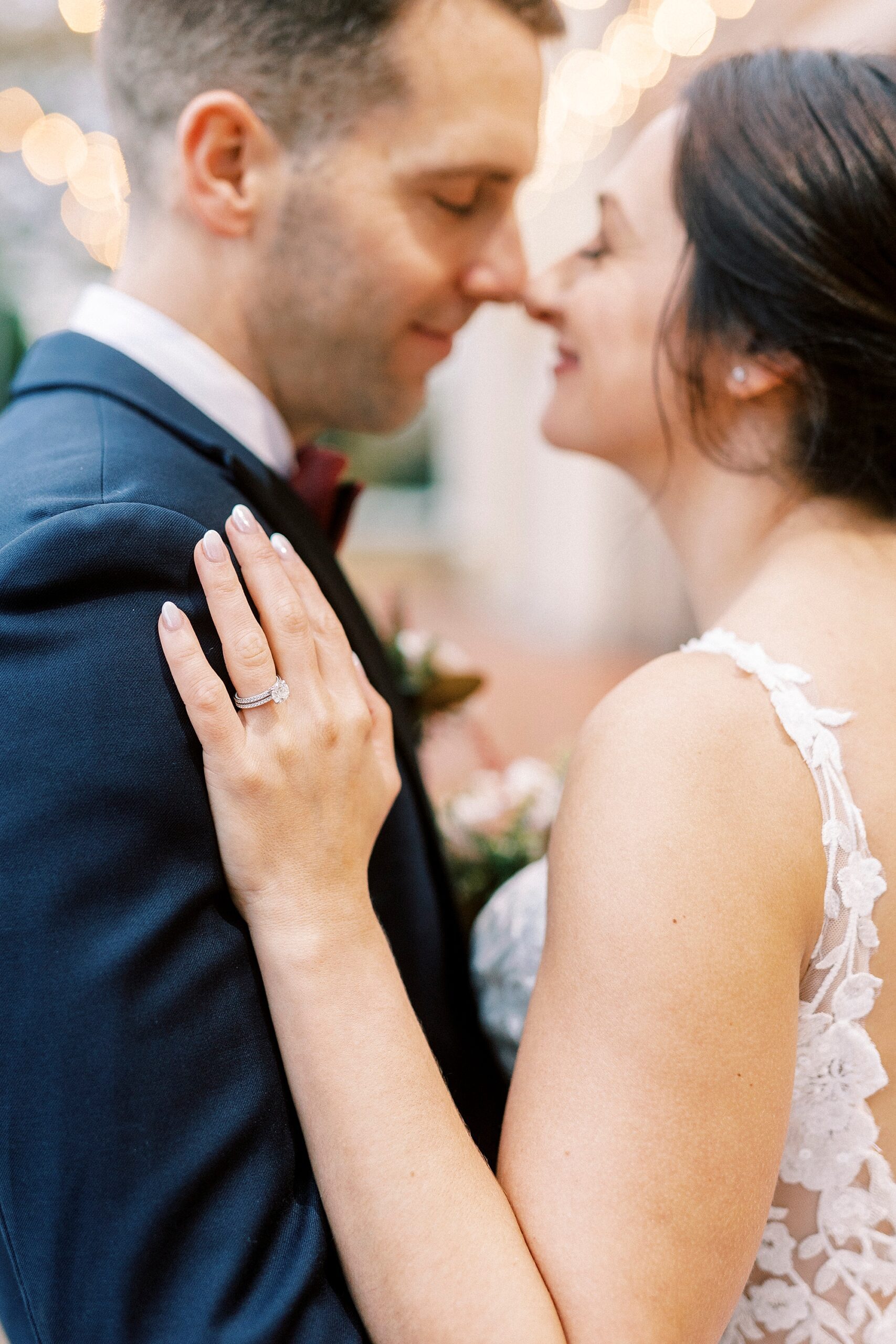 bride and groom hug with bride's hand on his shoulder showing off ring 