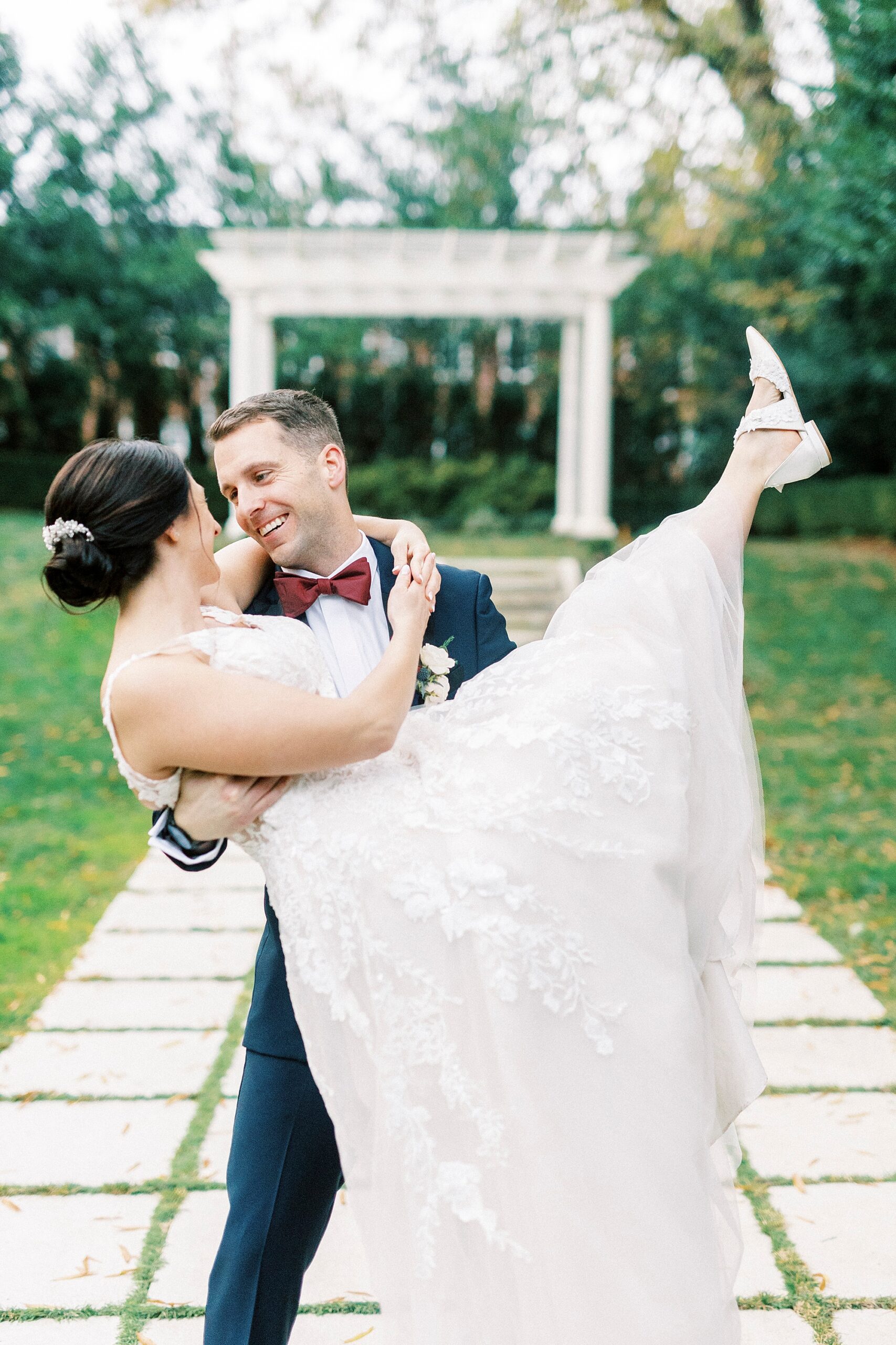 groom picks up bride in front of arch in gardens at Separk Mansion