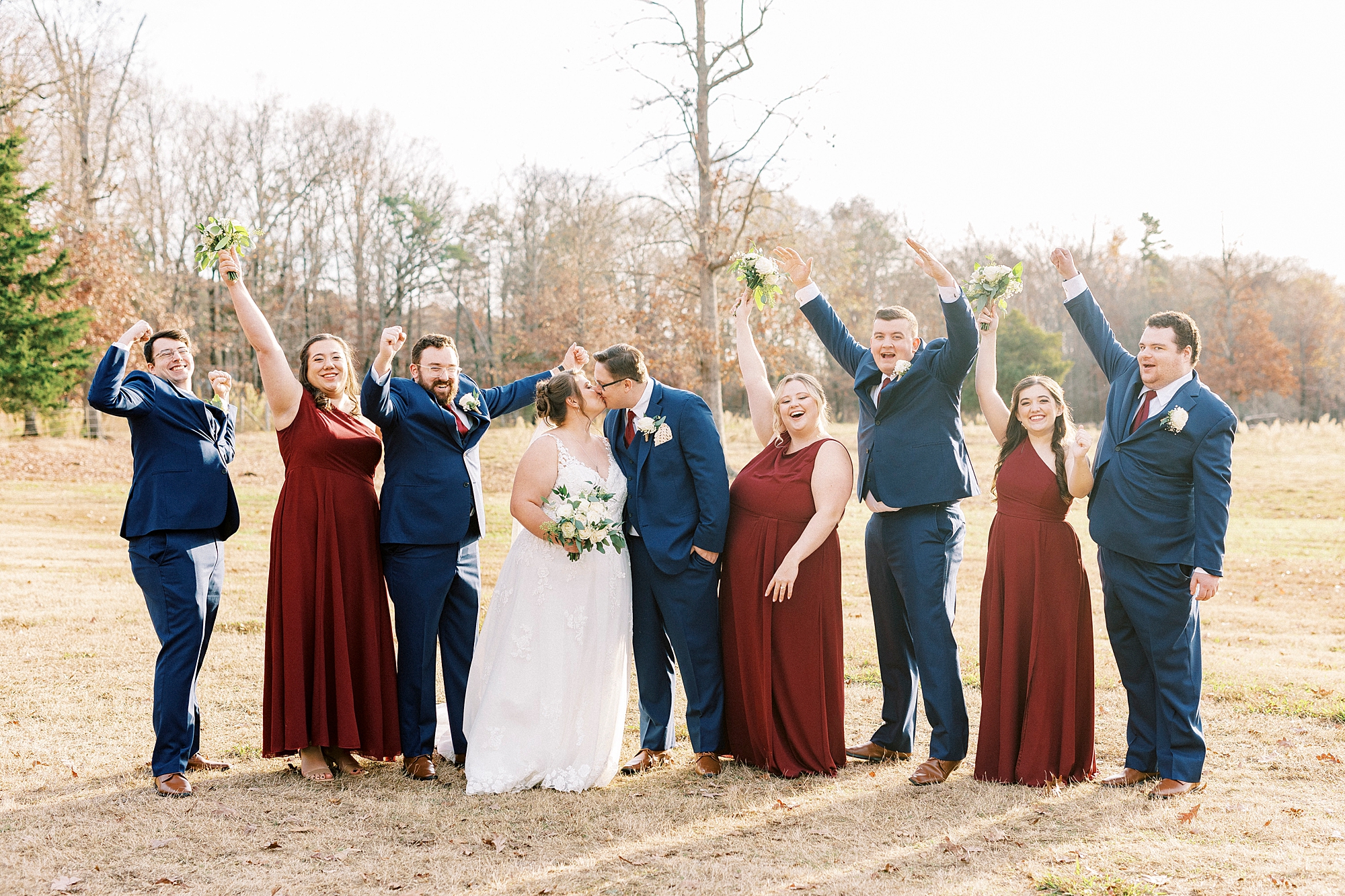 newlyweds kiss while wedding party cheers on the lawn at the Farm at Brusharbor