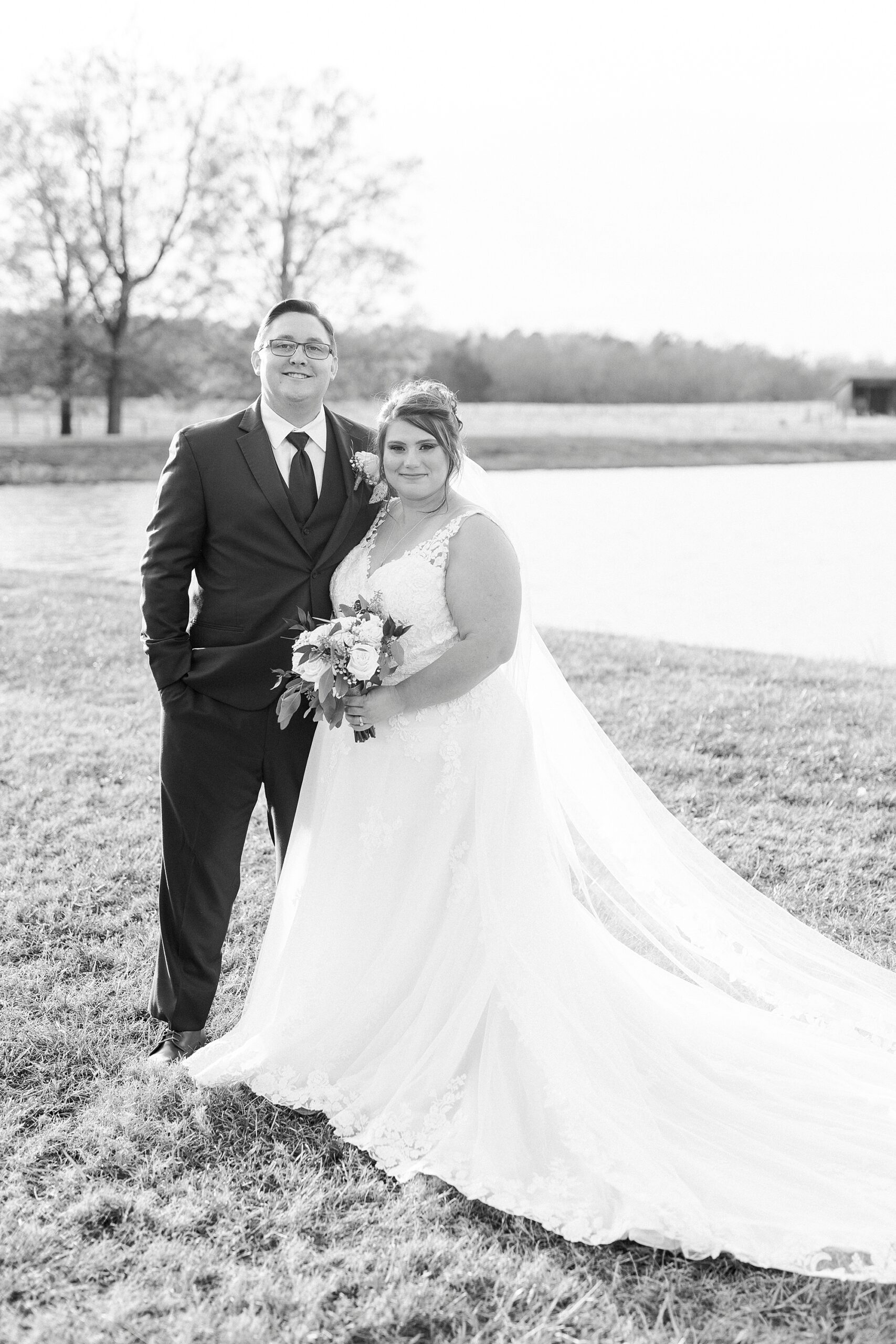 bride and groom stand together hugging near pond at the Farm at Brusharbor