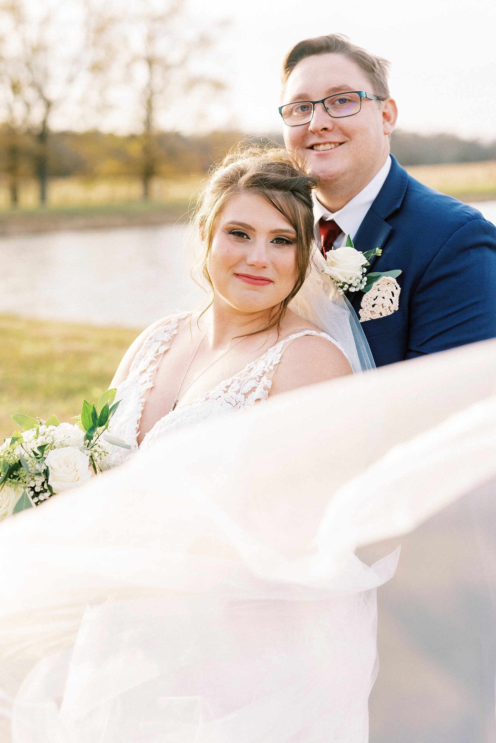groom hugs bride to his front with her veil floating before them 