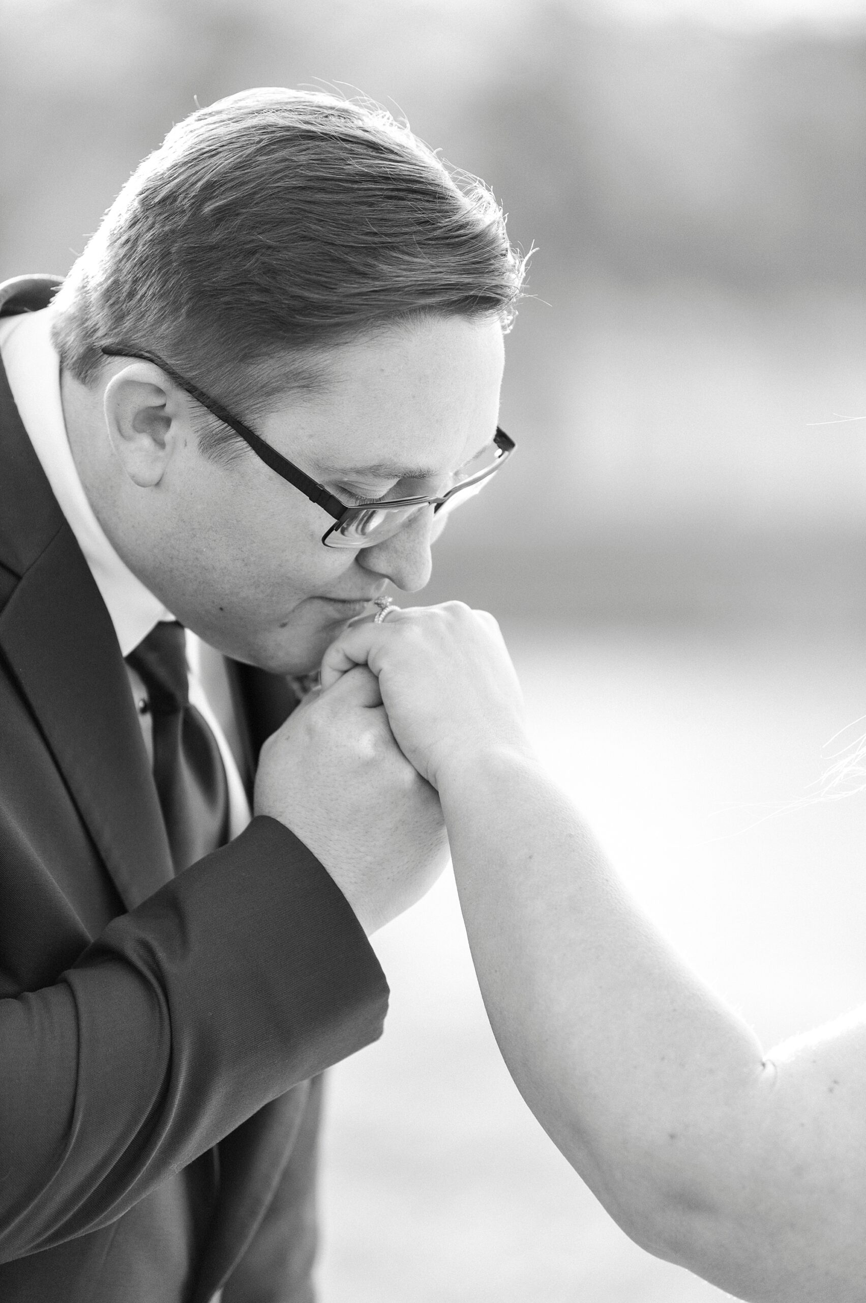 groom kisses bride's hand during wedding portraits 