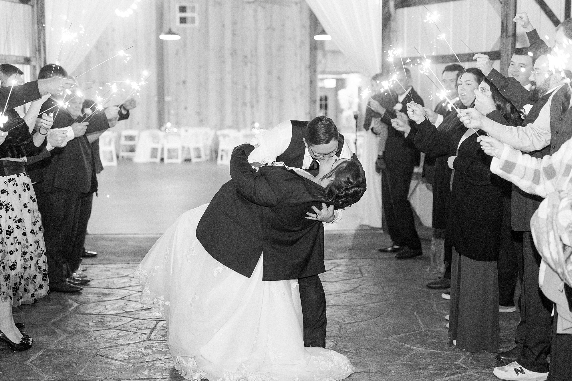 groom dips bride wearing his suit jacket during sparkler exit at the Farm at Brusharbor