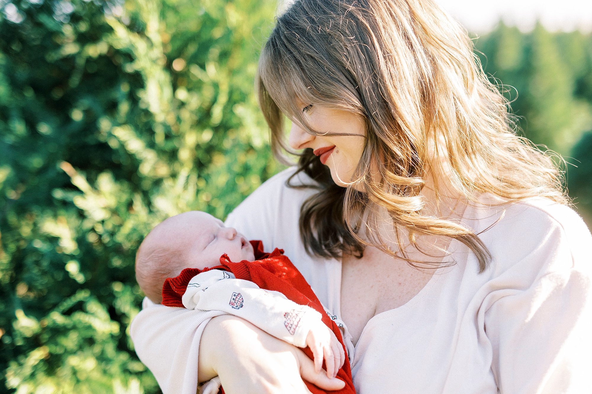 mom smiles down at baby in her arms during Penland Christmas Tree farm mini sessions 