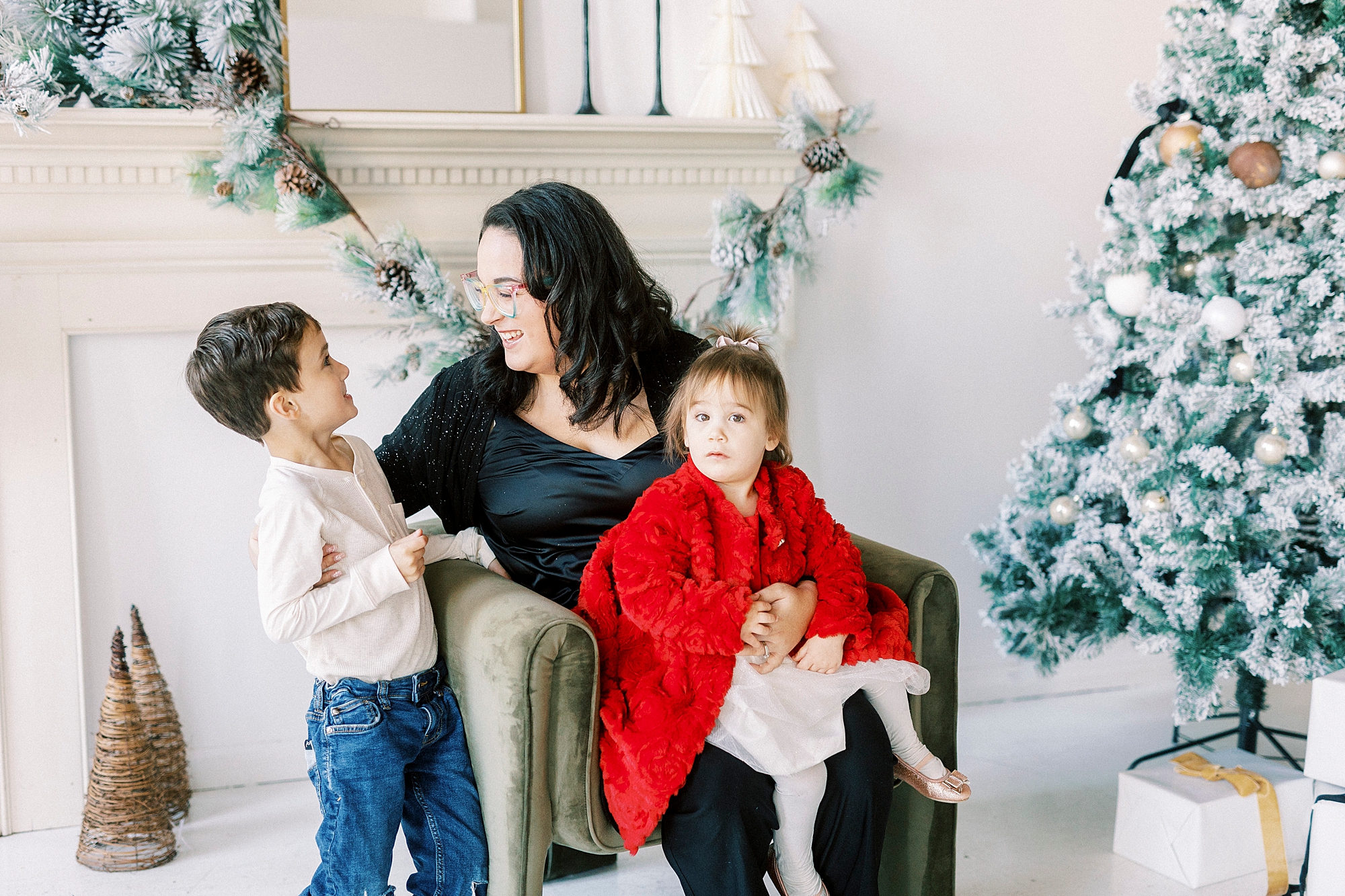 mom hugs two children in front of Christmas tree during portraits in Downtown Concord NC studio