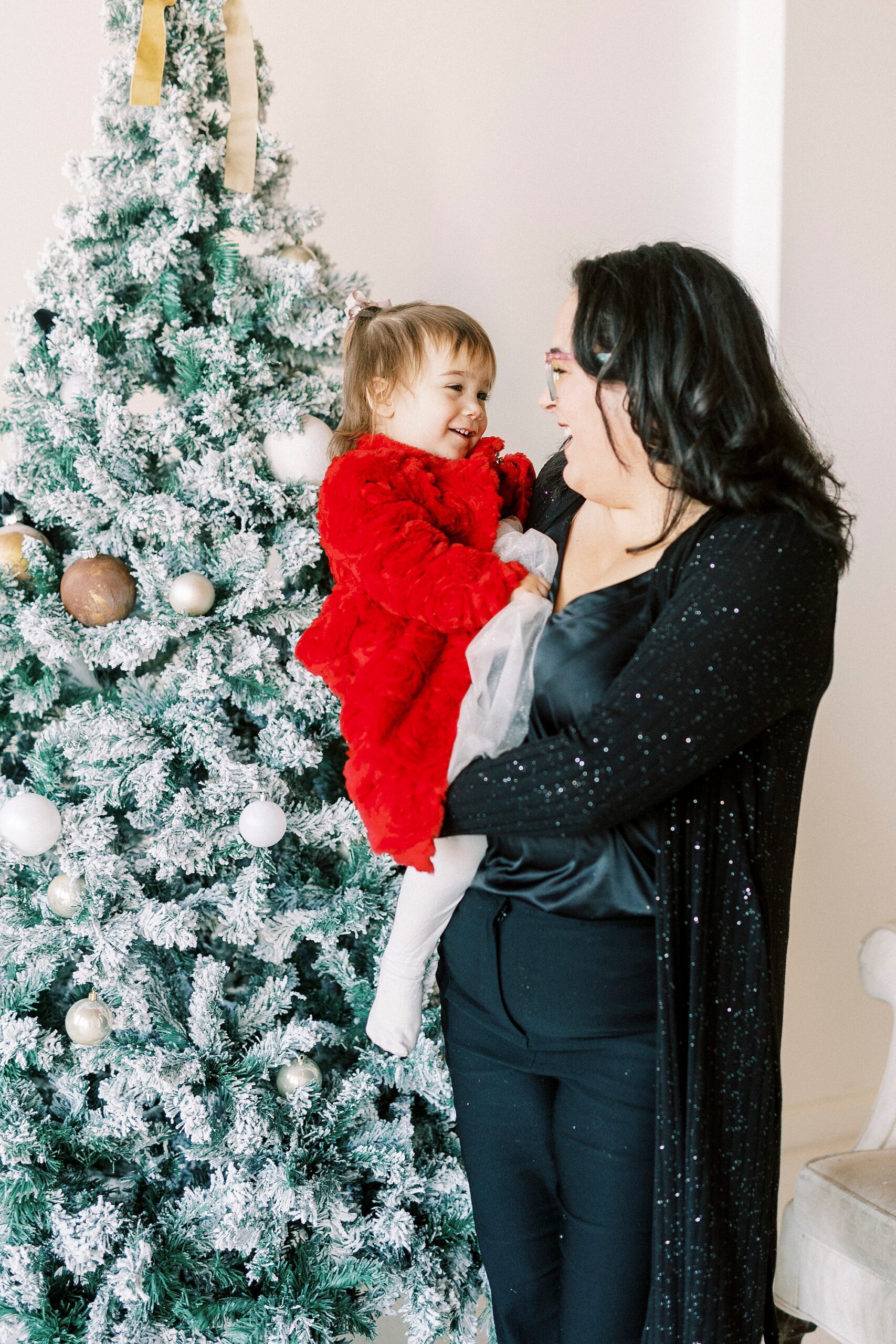 mom and daughter hug together by Christmas tree in Concord NC