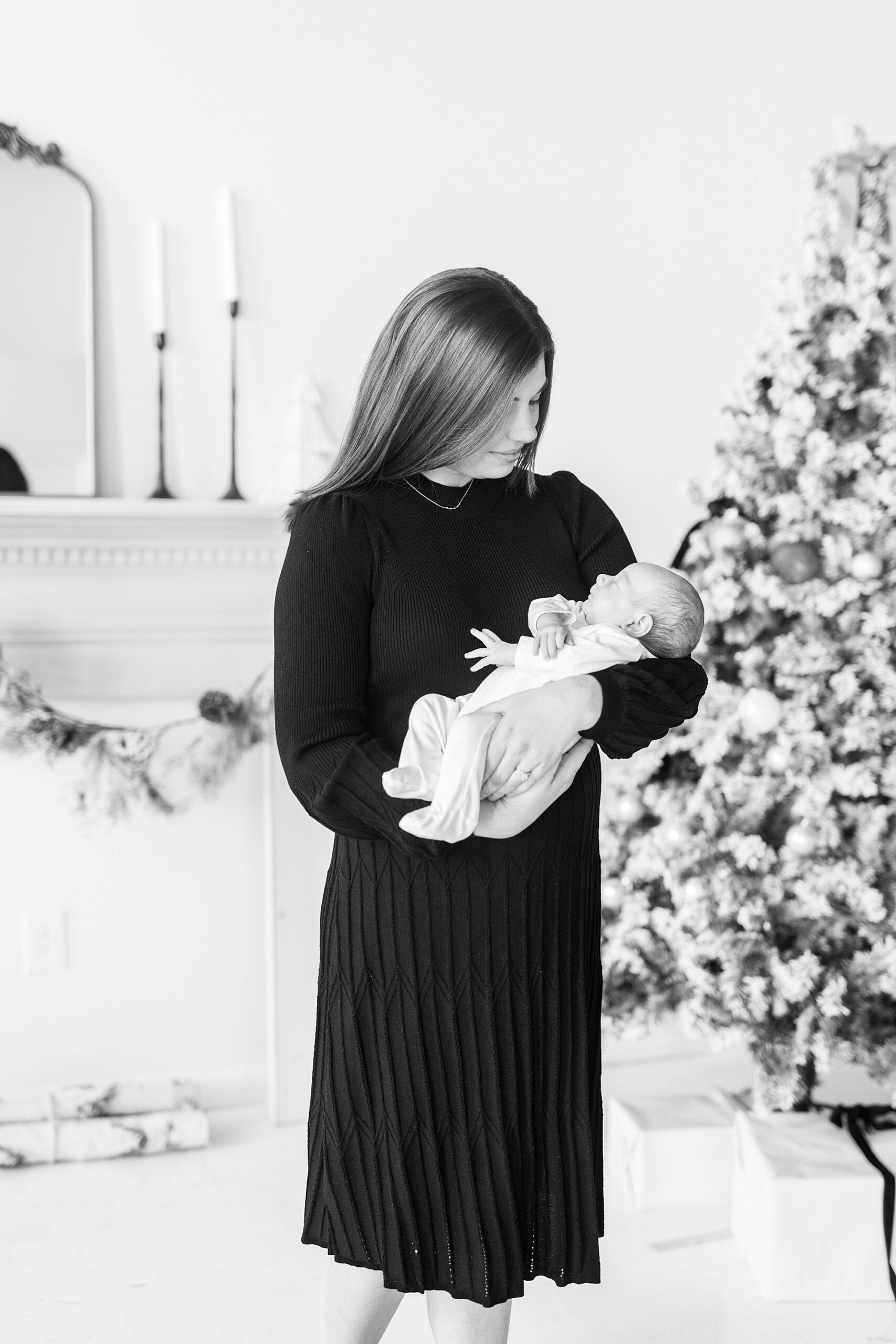 woman holds son by tree during studio Christmas portraits in Downtown Concord