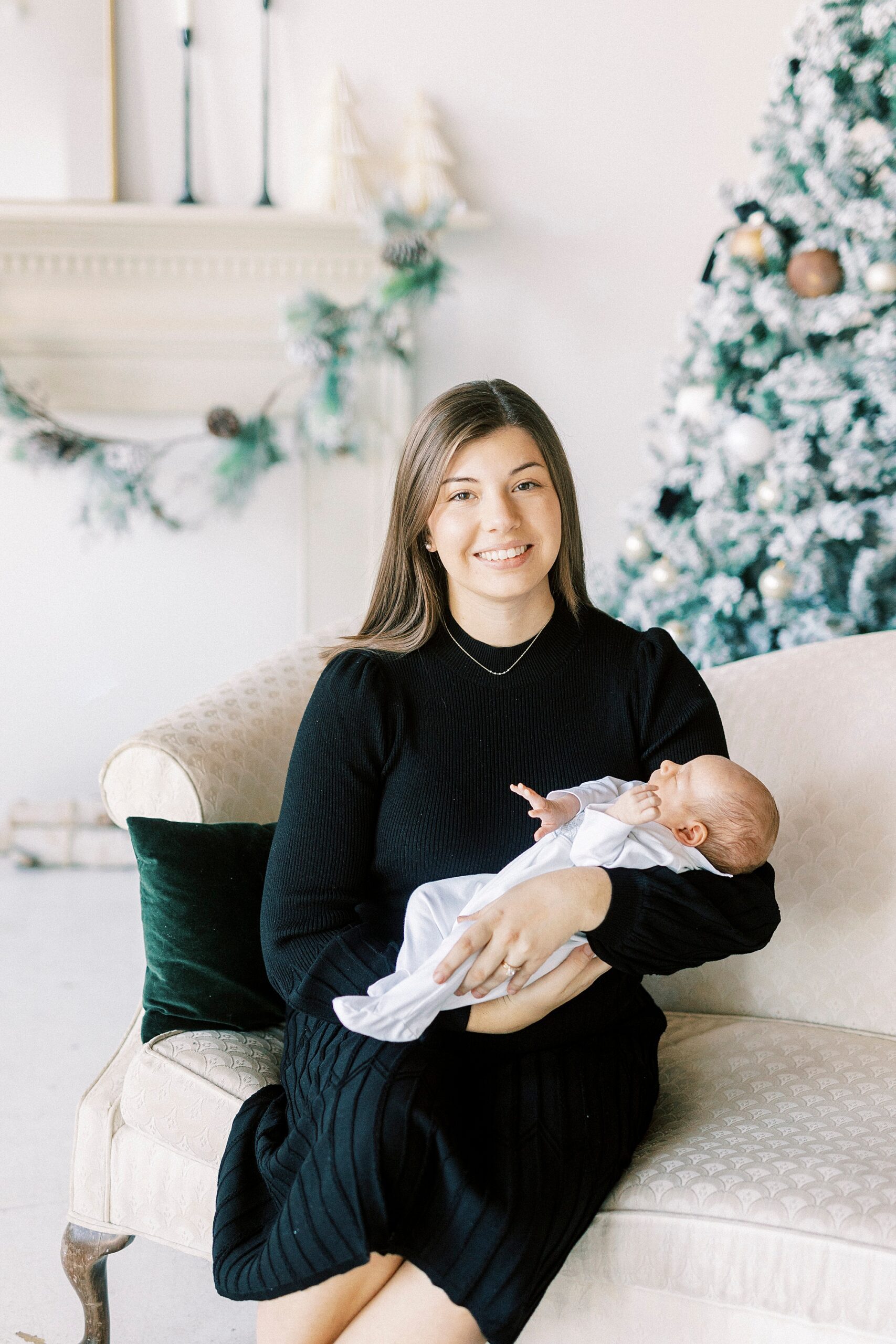woman in black dress holds newborn baby during studio portraits in Concord NC