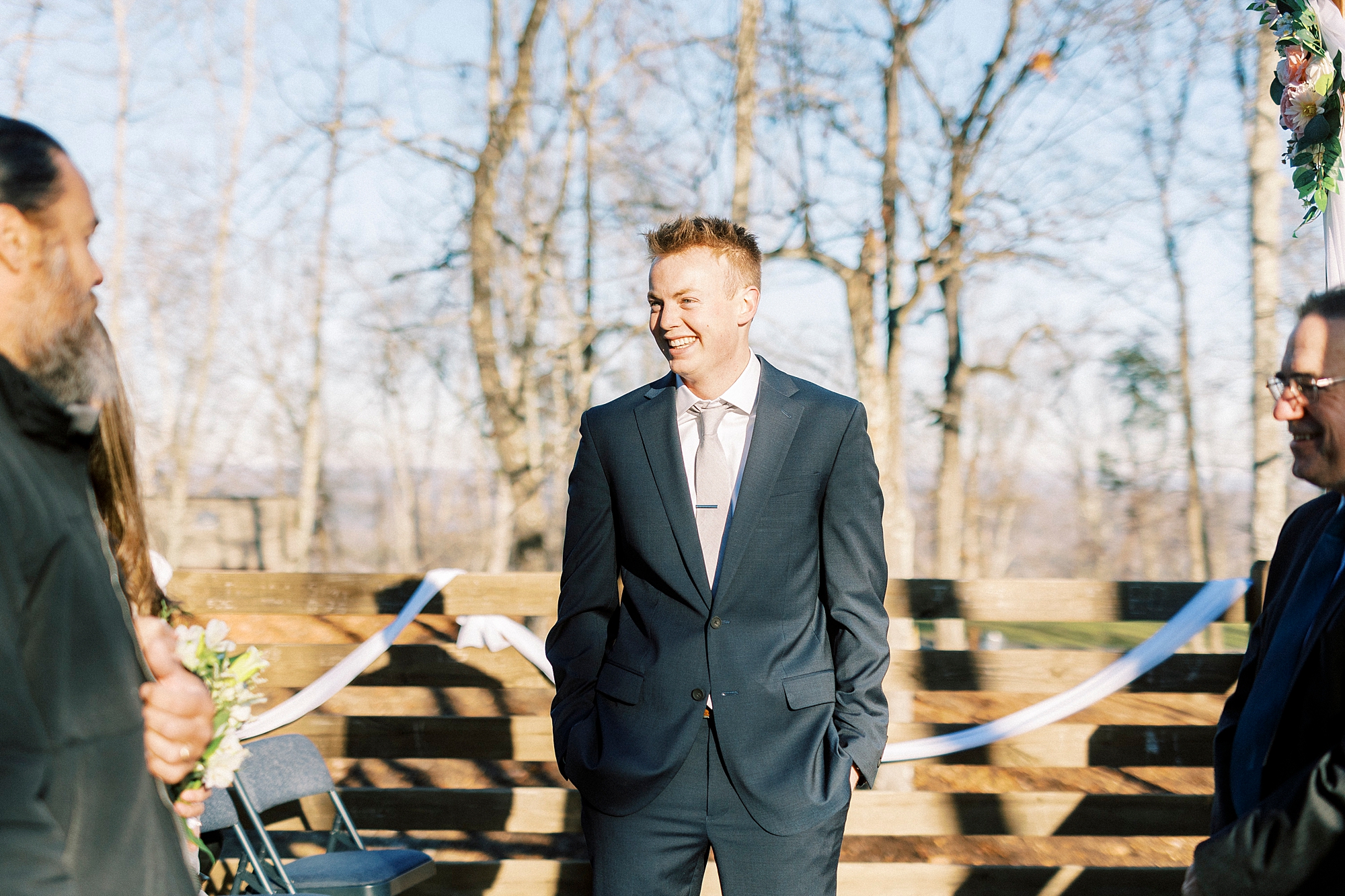 groom waits with hands in pockets for bride on Morrow Mountain