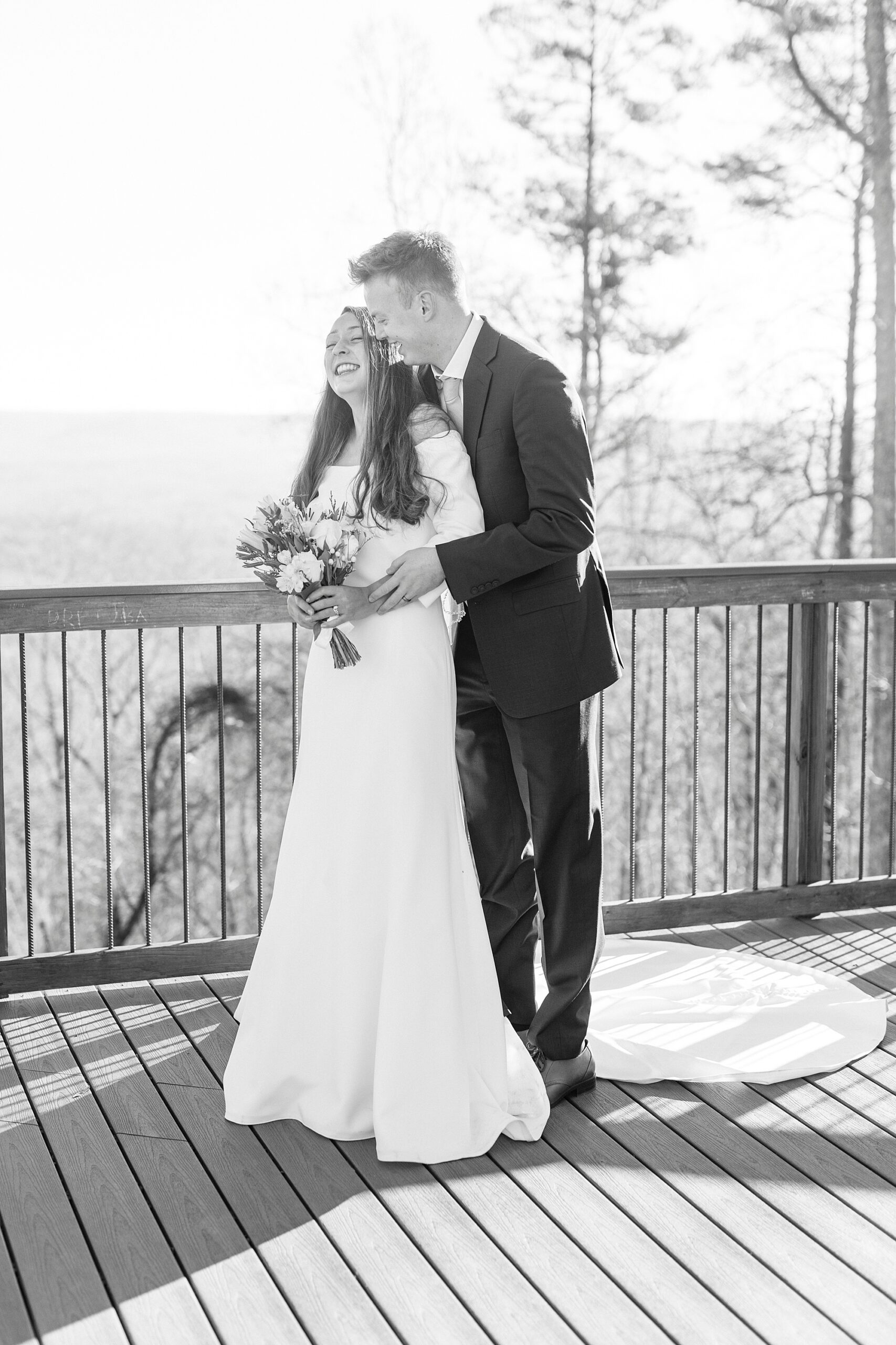 groom hugs bride from behind making her laugh during portraits on Morrow Mountain
