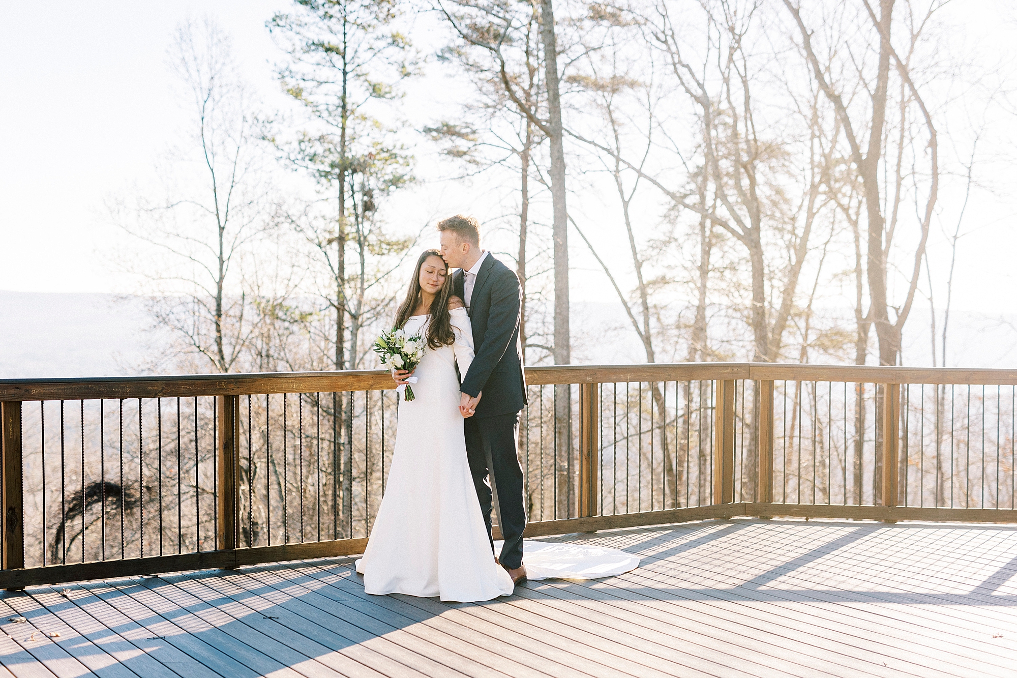 groom kisses bride's head hugging her from behind at Morrow Mountain