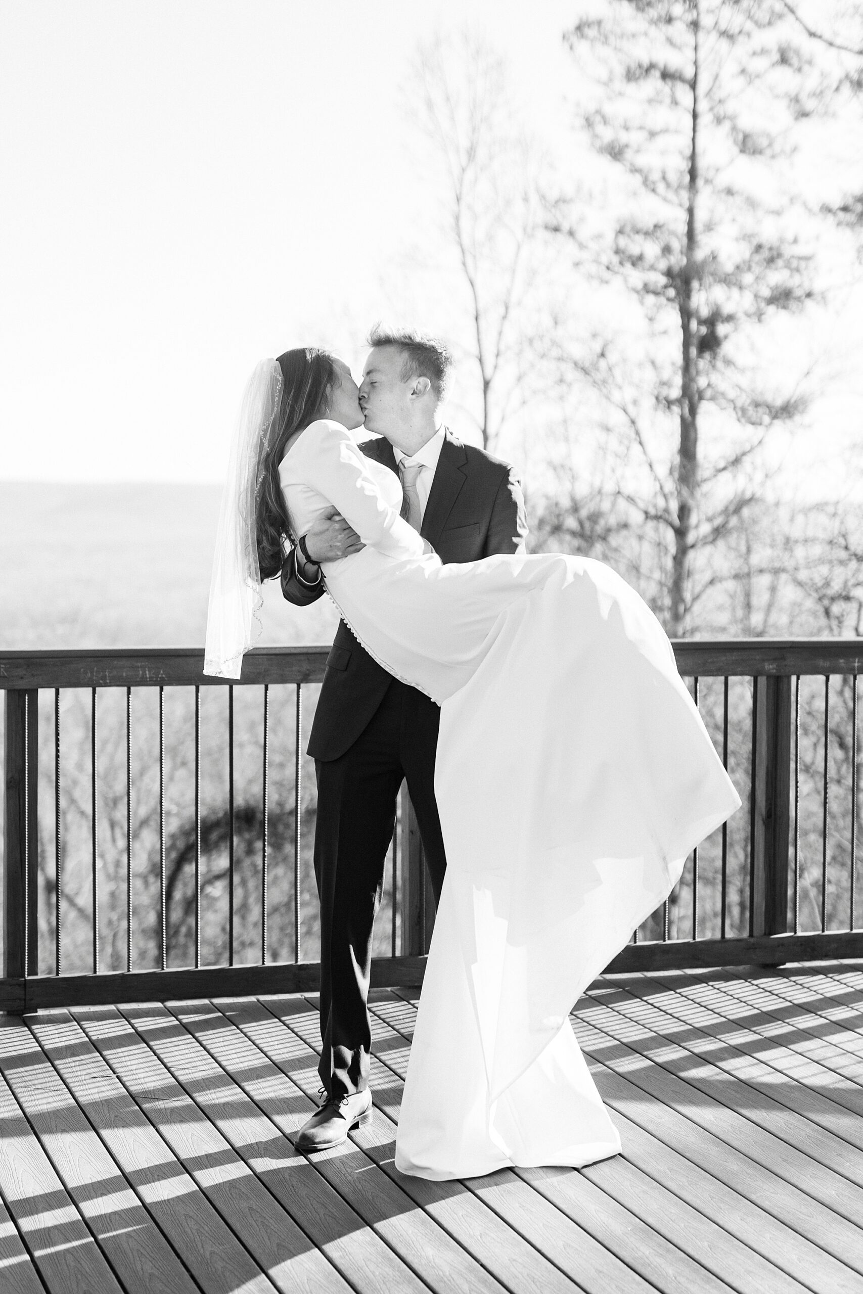 groom picks up bride holding her during wedding day on Morrow Mountain