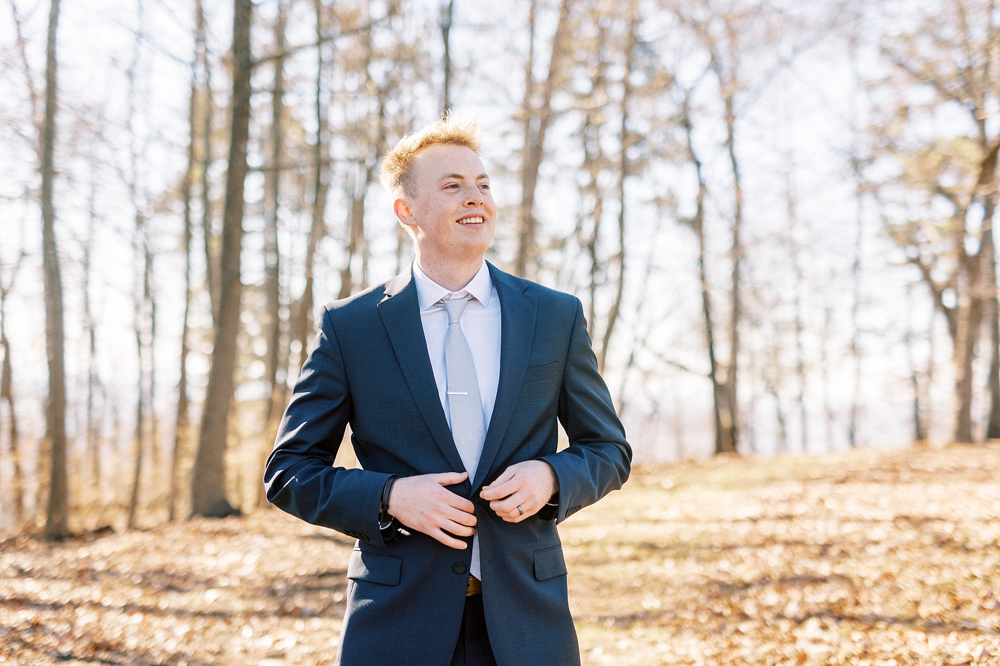 groom adjusts buttons of navy suit jacket in Albemarle NC