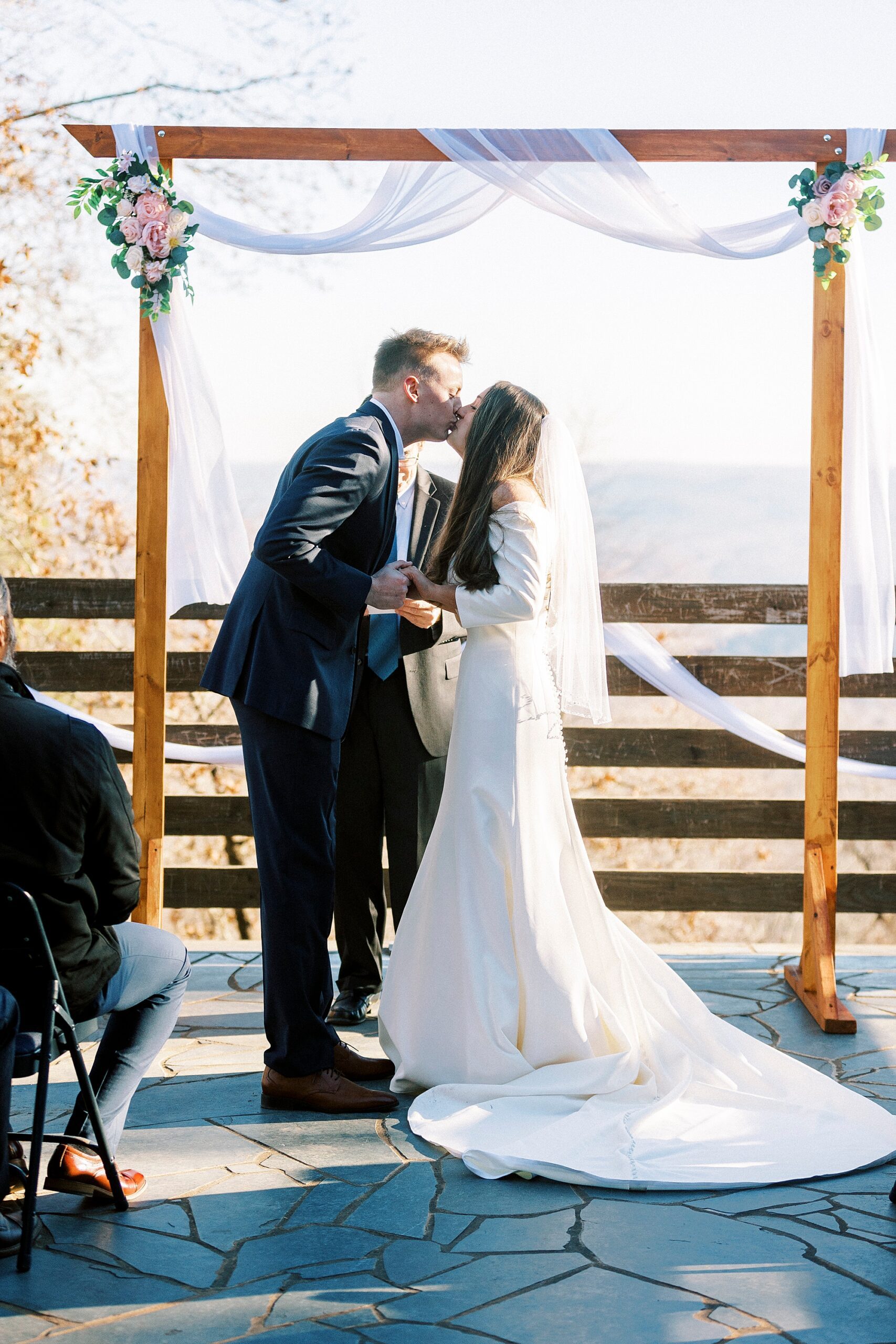 bride and groom kiss under wooden arbor after early morning wedding ceremony on Morrow Mountain