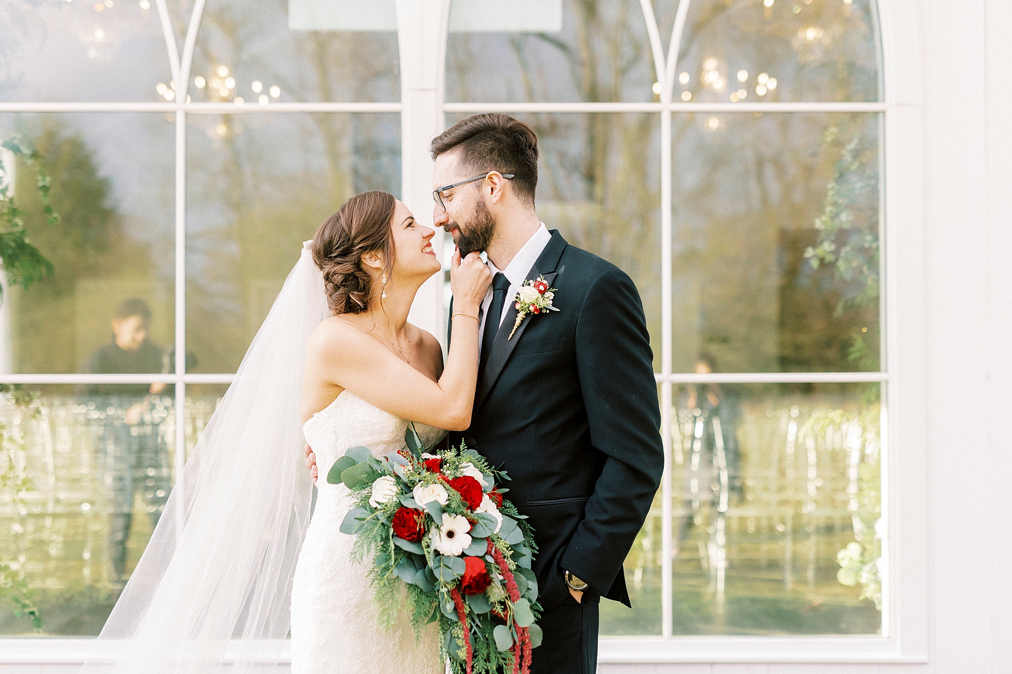 bride and groom hug by chapel windows at Chickadee Hill Farms